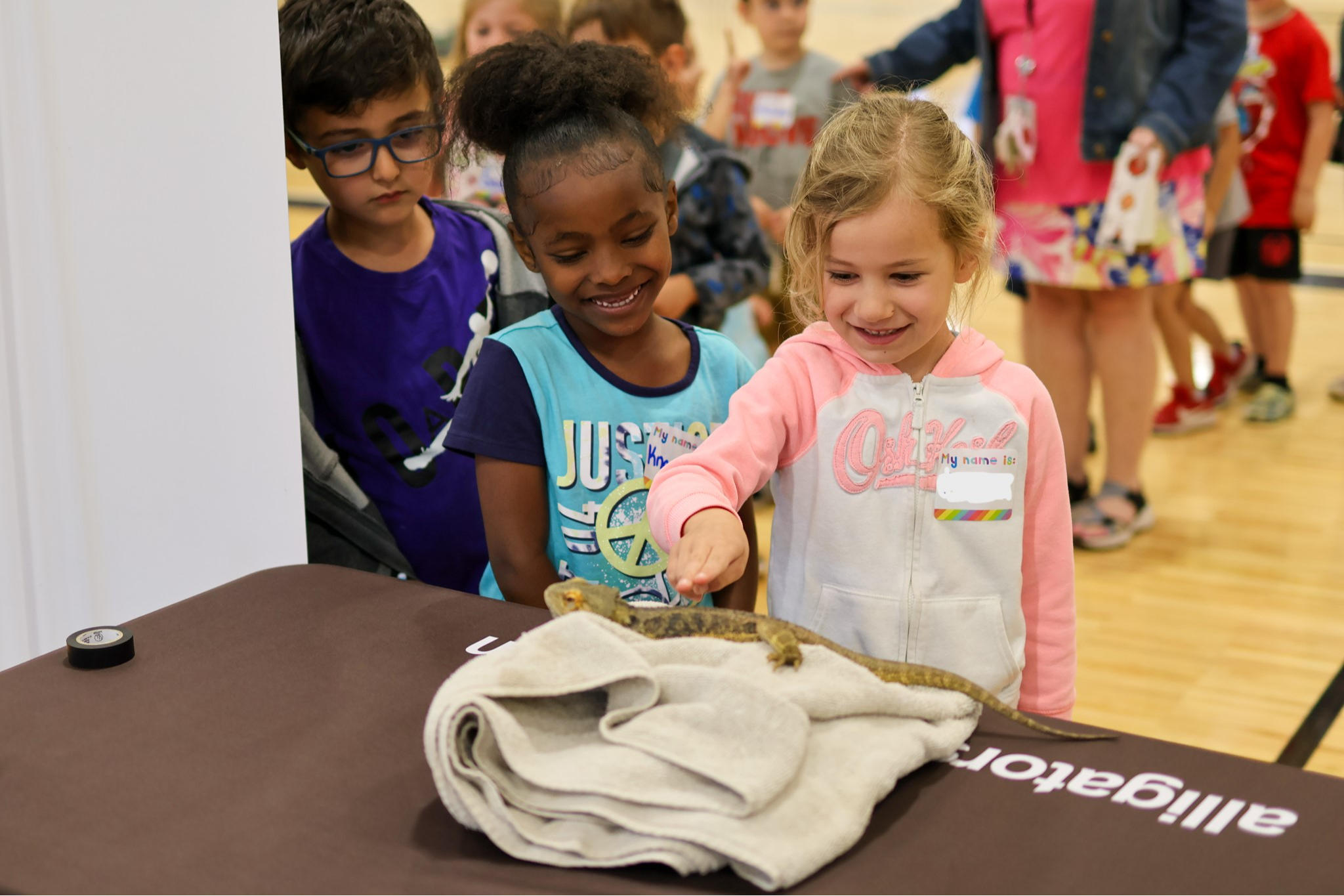 three students touch a bearded dragon