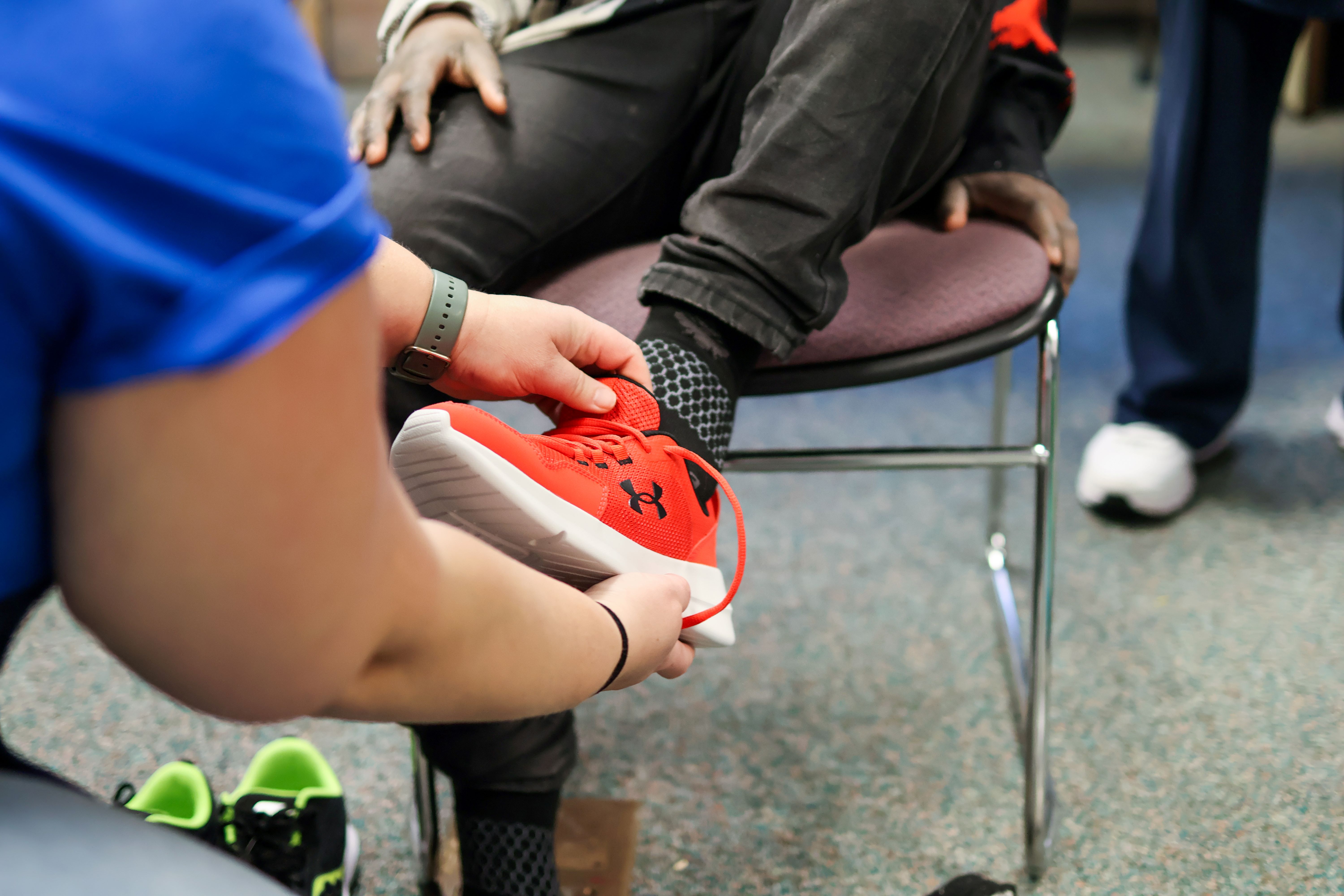 a woman puts a shoe on a student