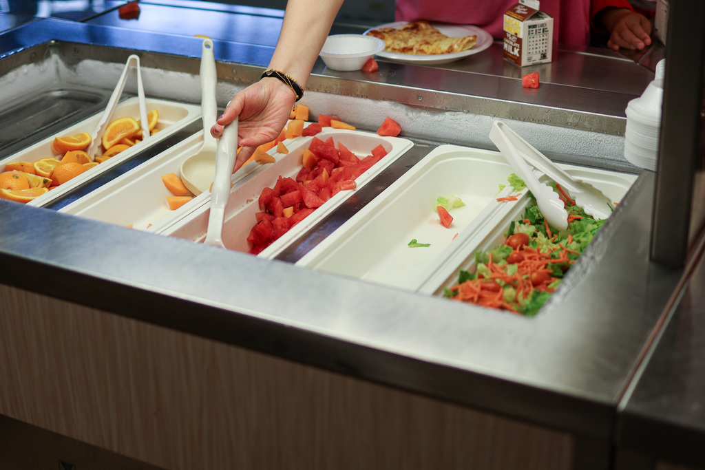 a person gets food from a salad bar