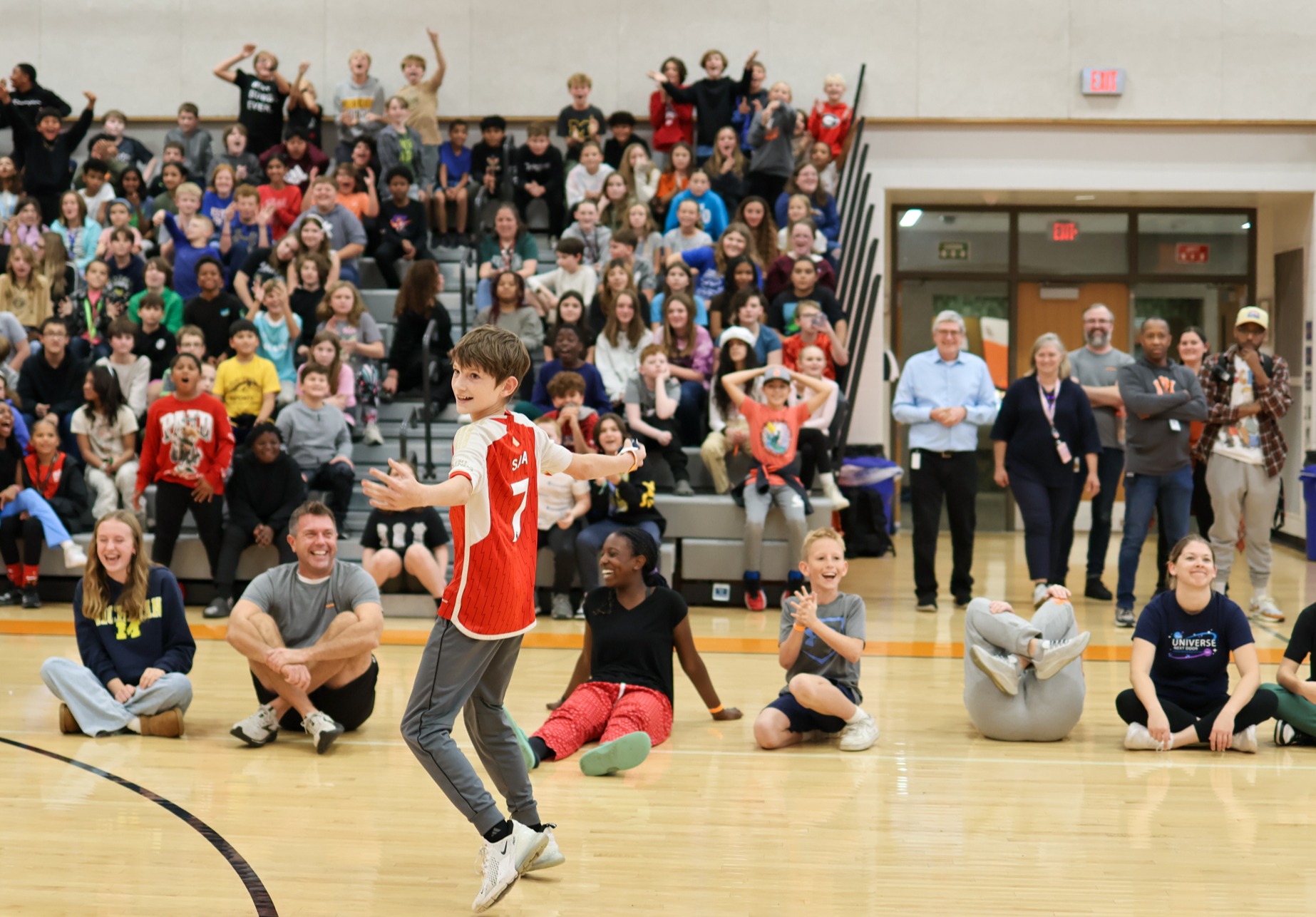 a boy cheers in front of a gym full of students