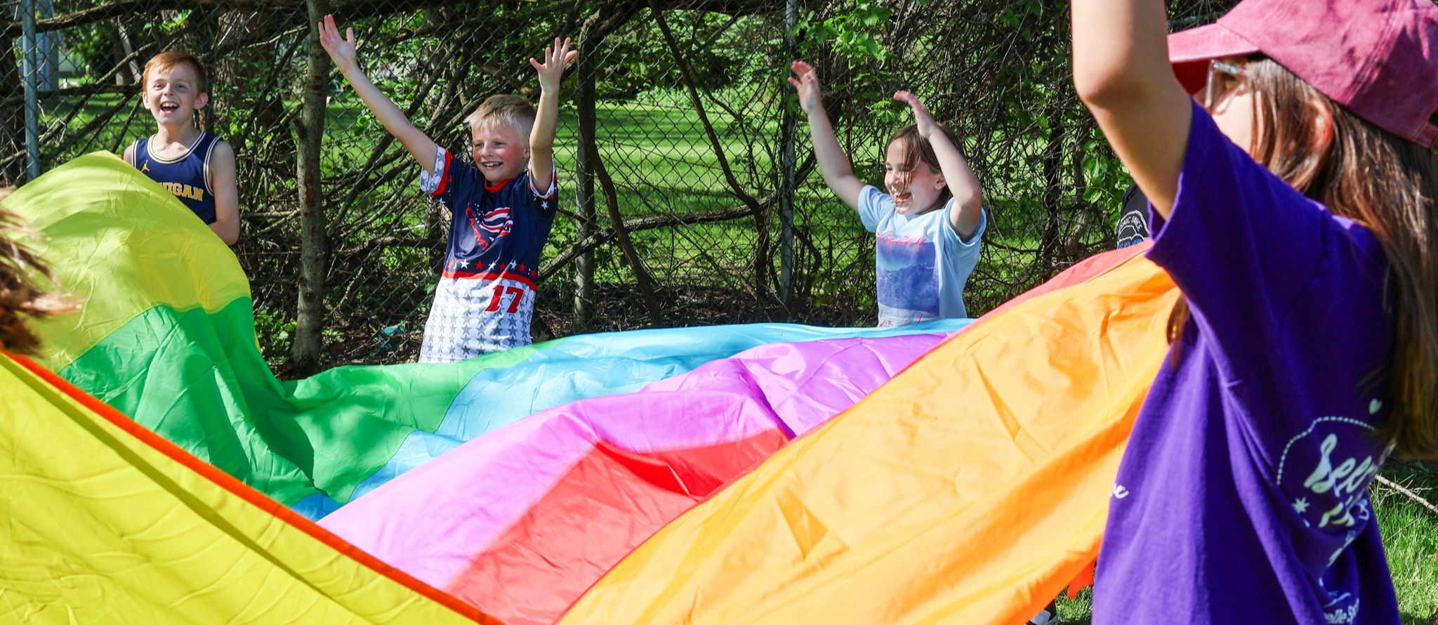 a girl smiles holding a colorful tarp