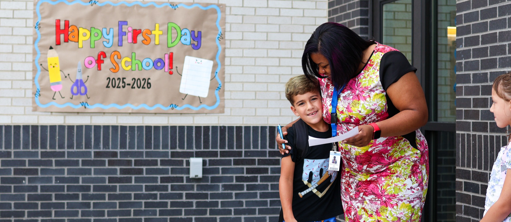 a teacher hugging a student outside a school