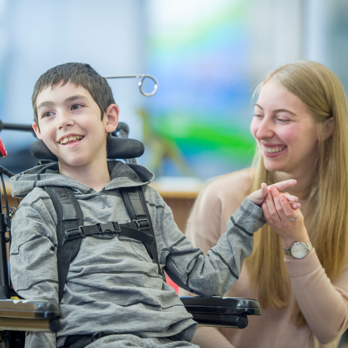 Student in a wheelchair smiling with teacher aide