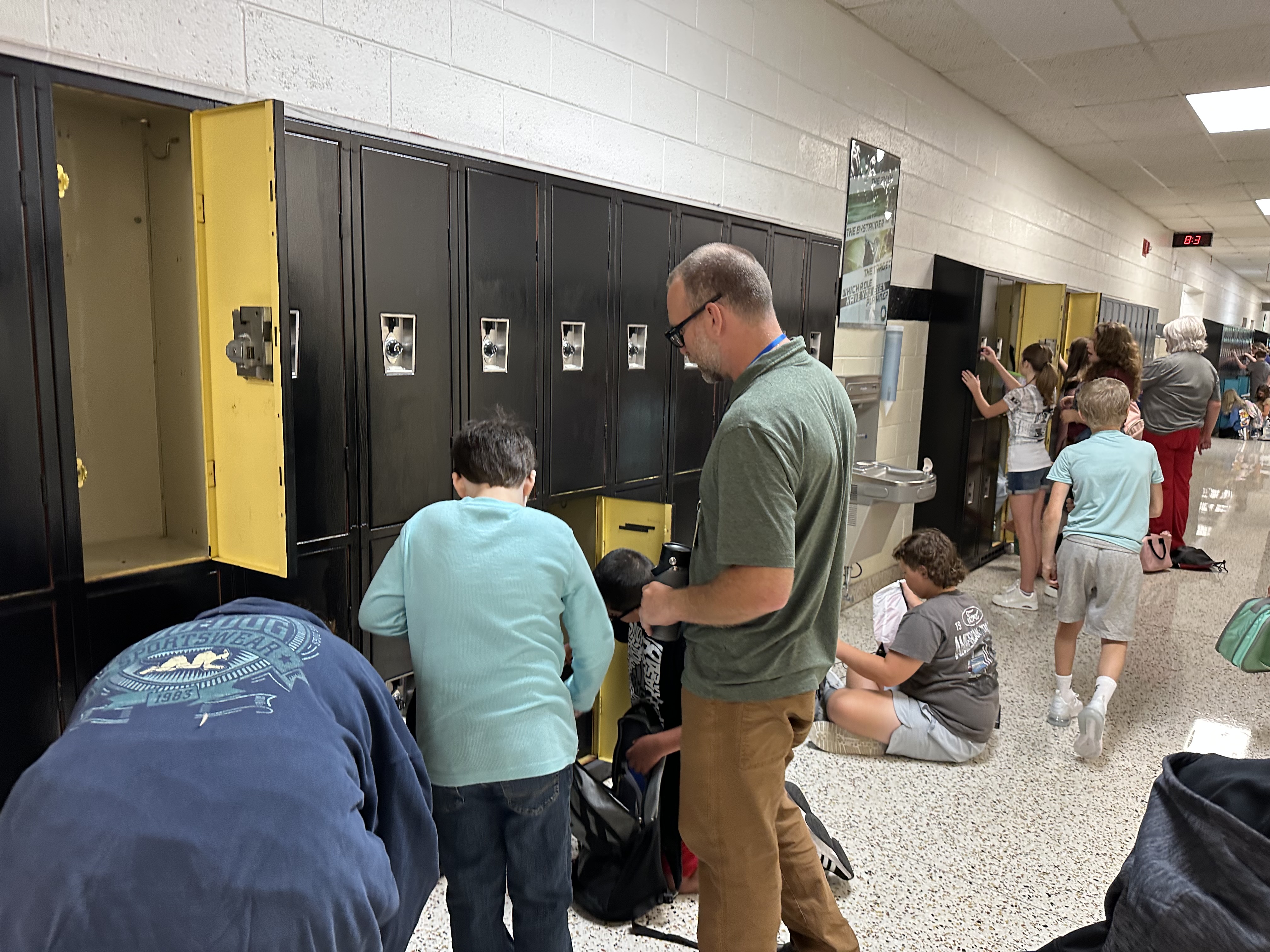 Staff members help students open lockers.