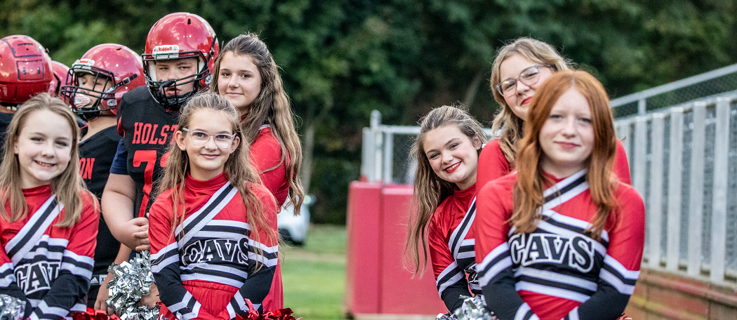 Cheerleaders stand on a football field.