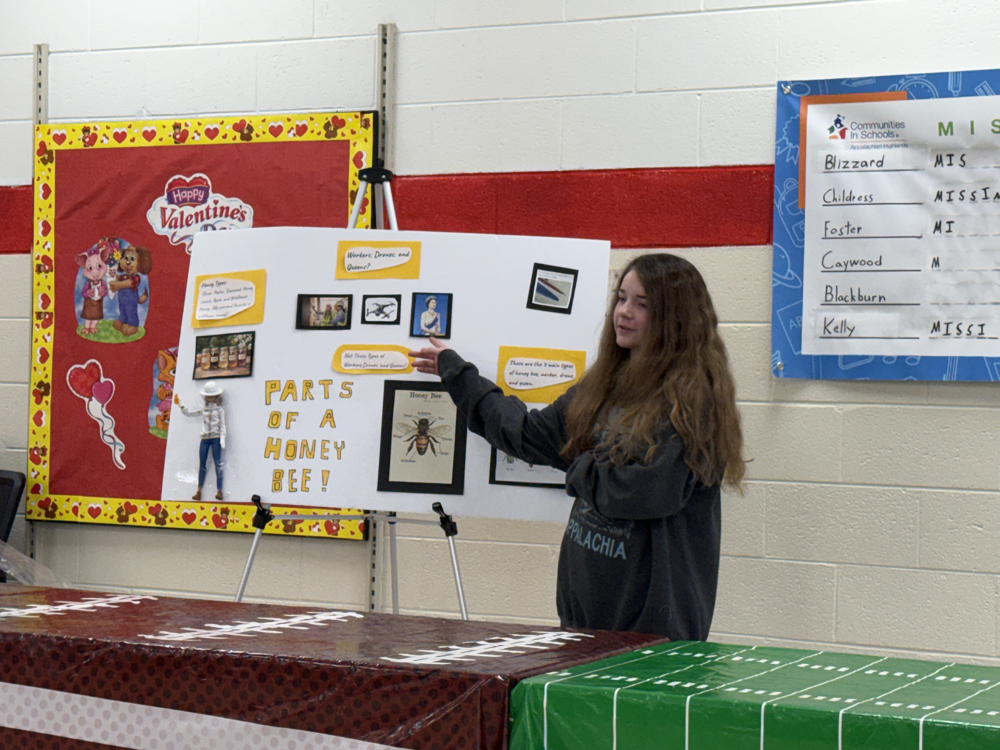 A student presents information about bees in a cafeteria.