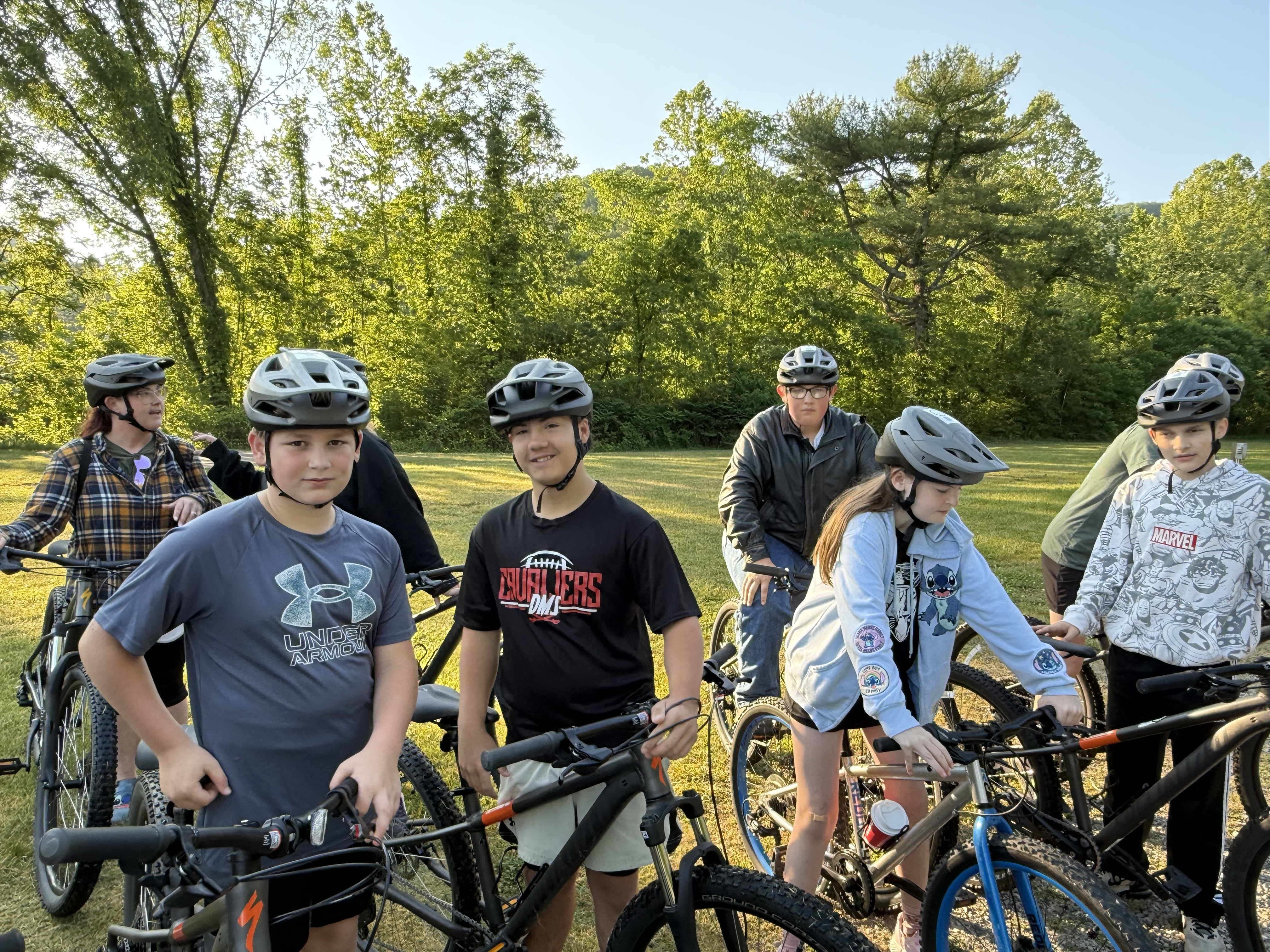 Students pose on bikes in a park.