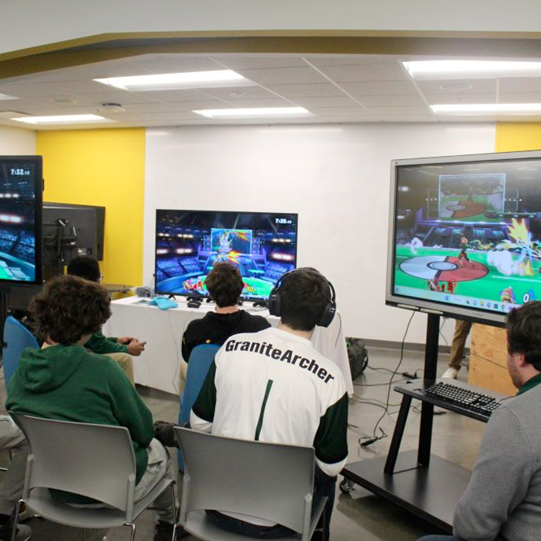 students sitting in front of 4 tv screens