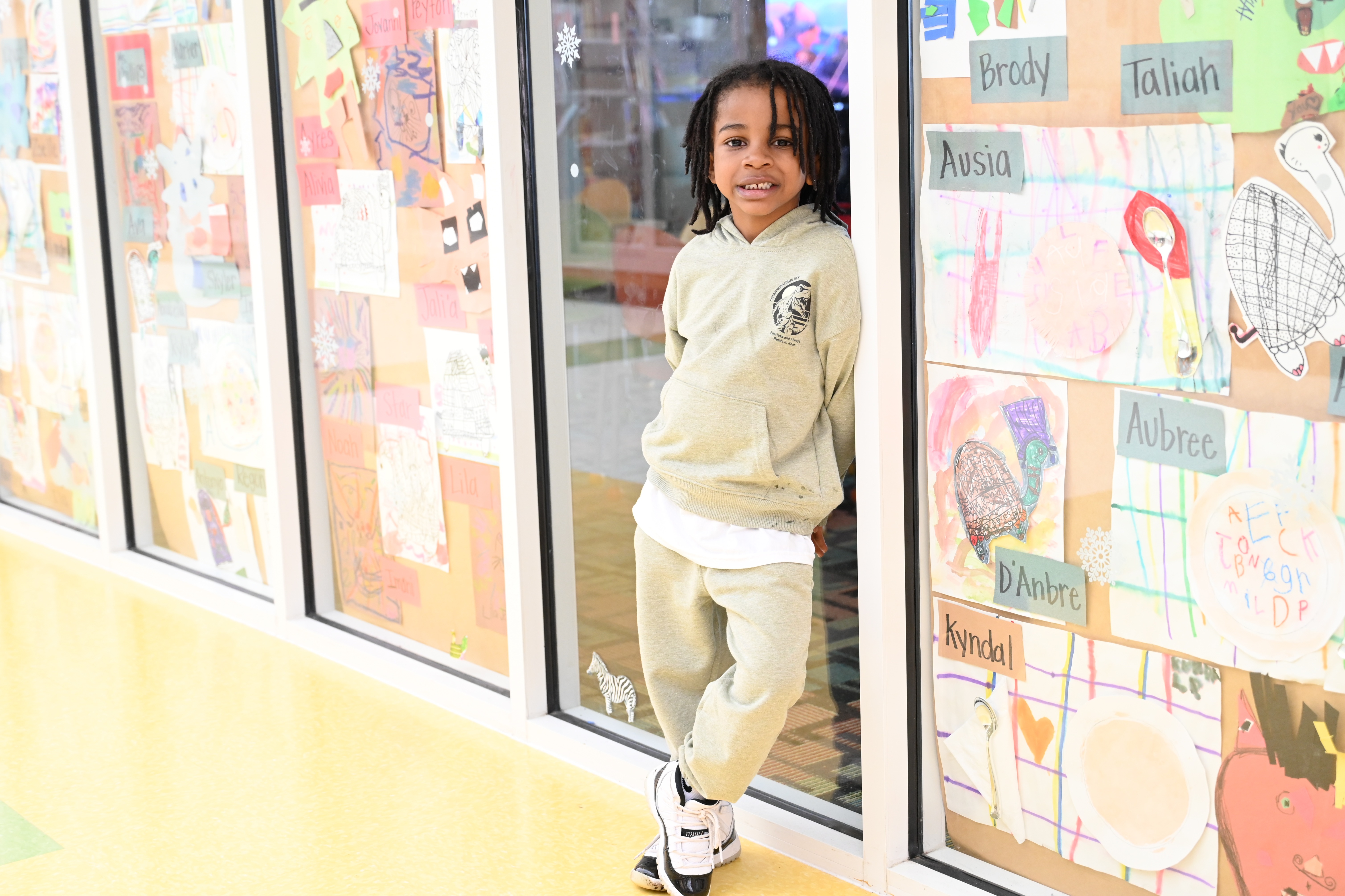 male student in the school hallway leaning against the student art work 