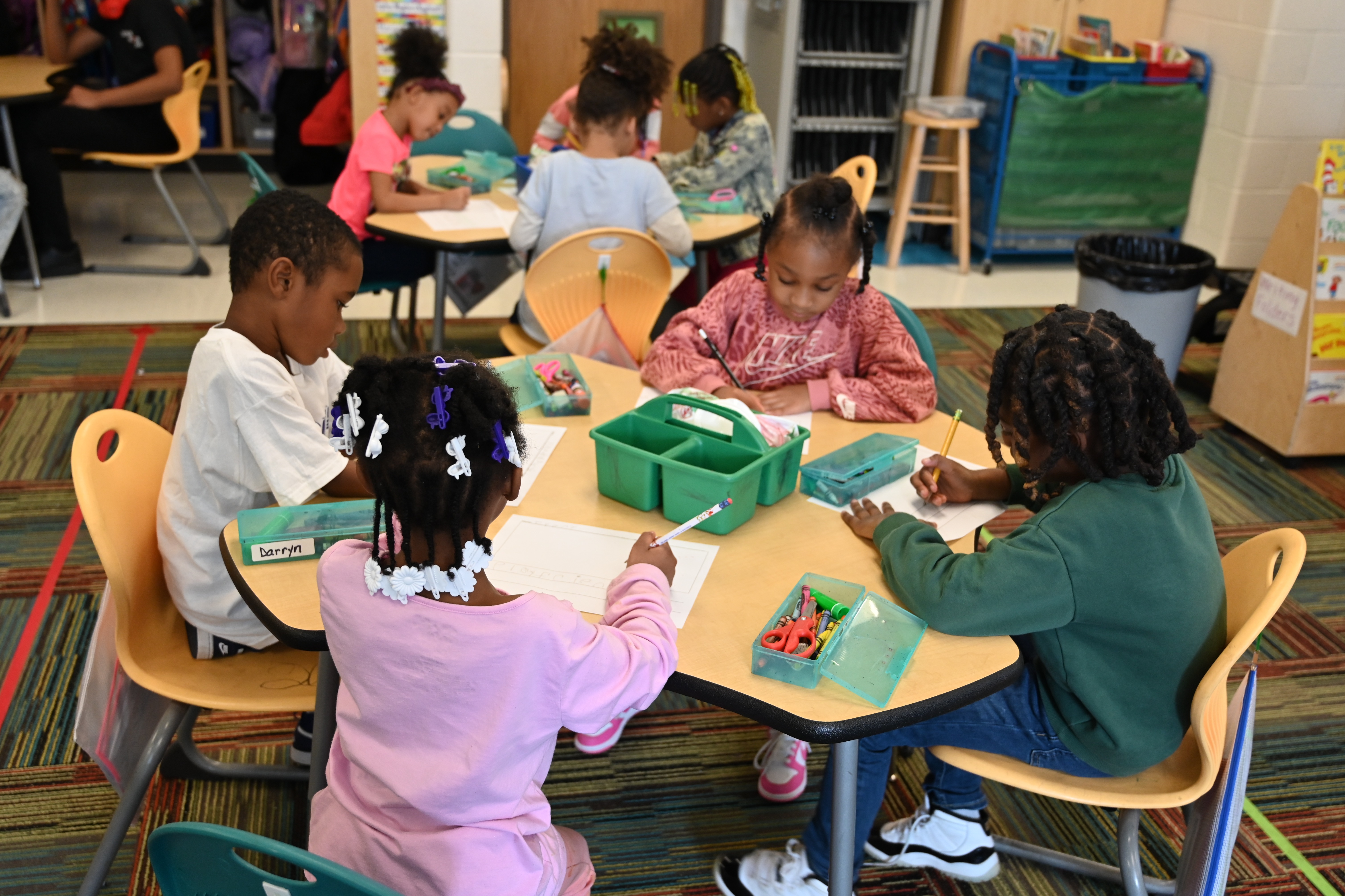 students working in groups coloring and writing 