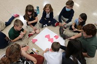 Students sitting in a circle working on an art project. 