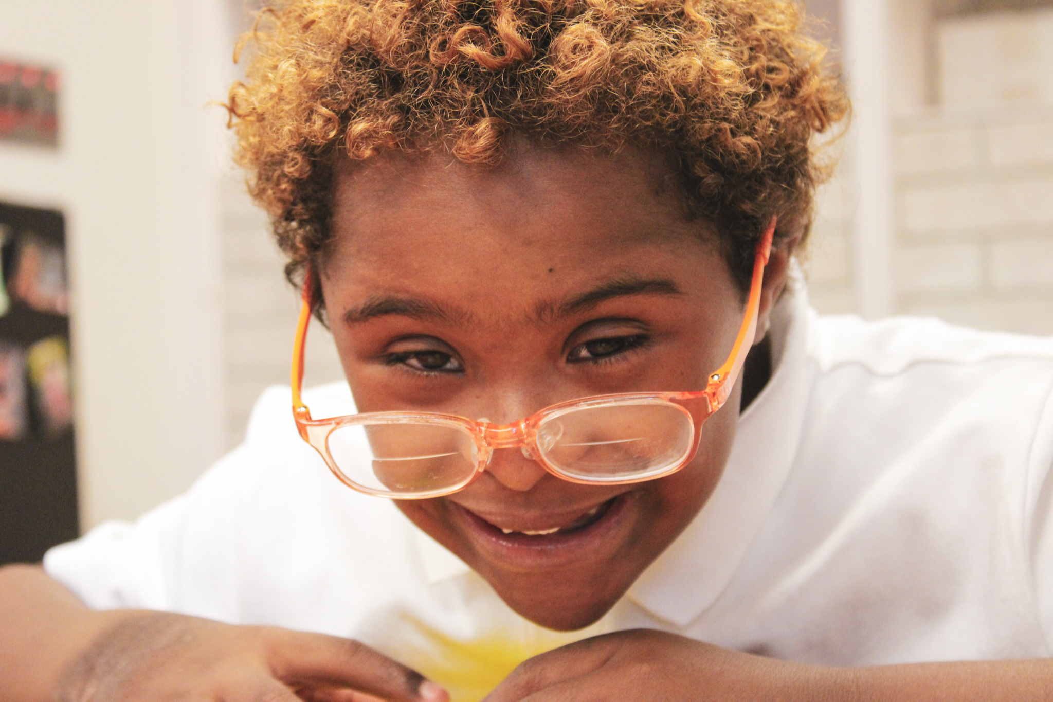 Child smiling with glasses on rim of nose