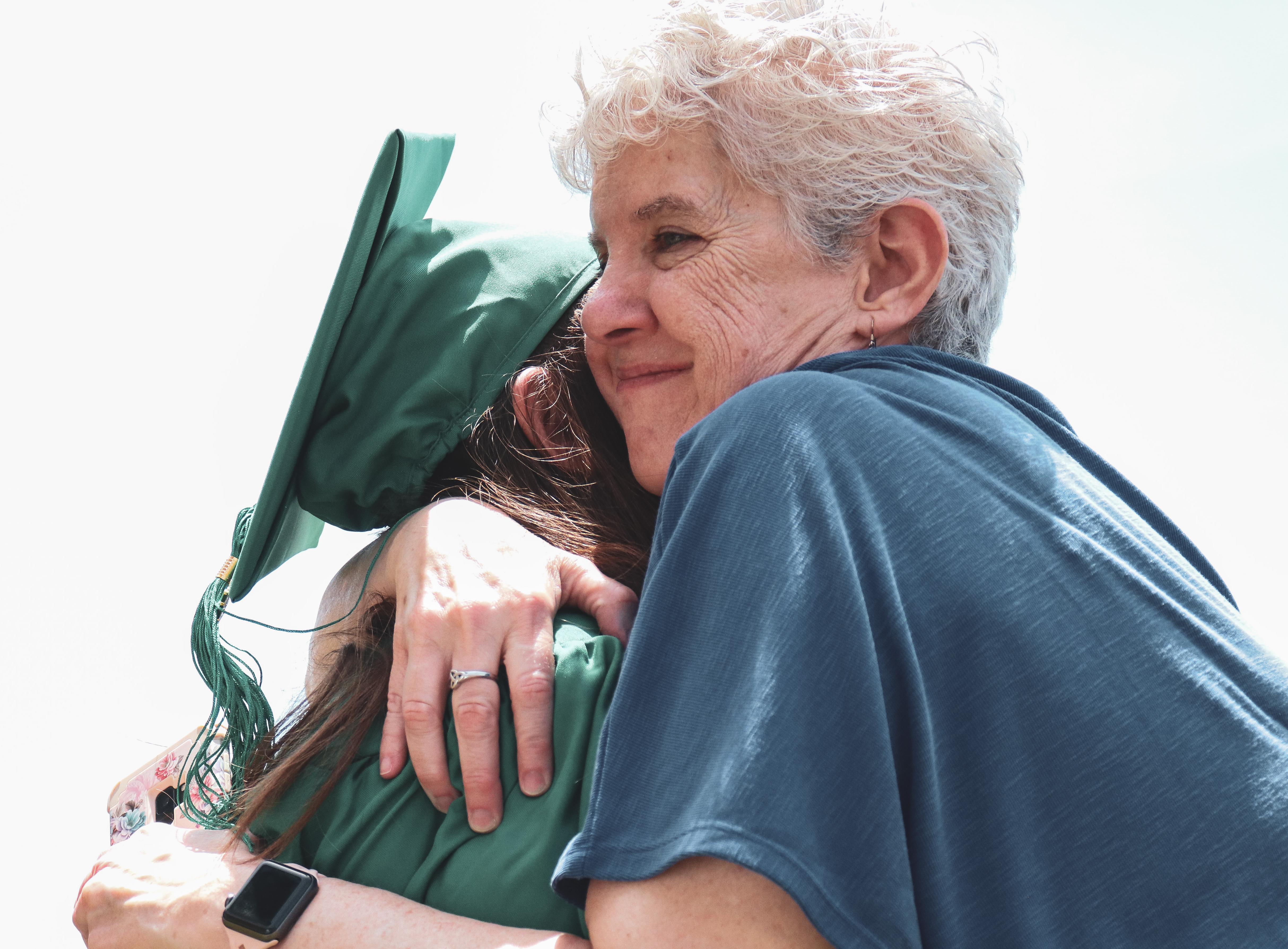 a high school teacher hugging a senior student after the graduation'