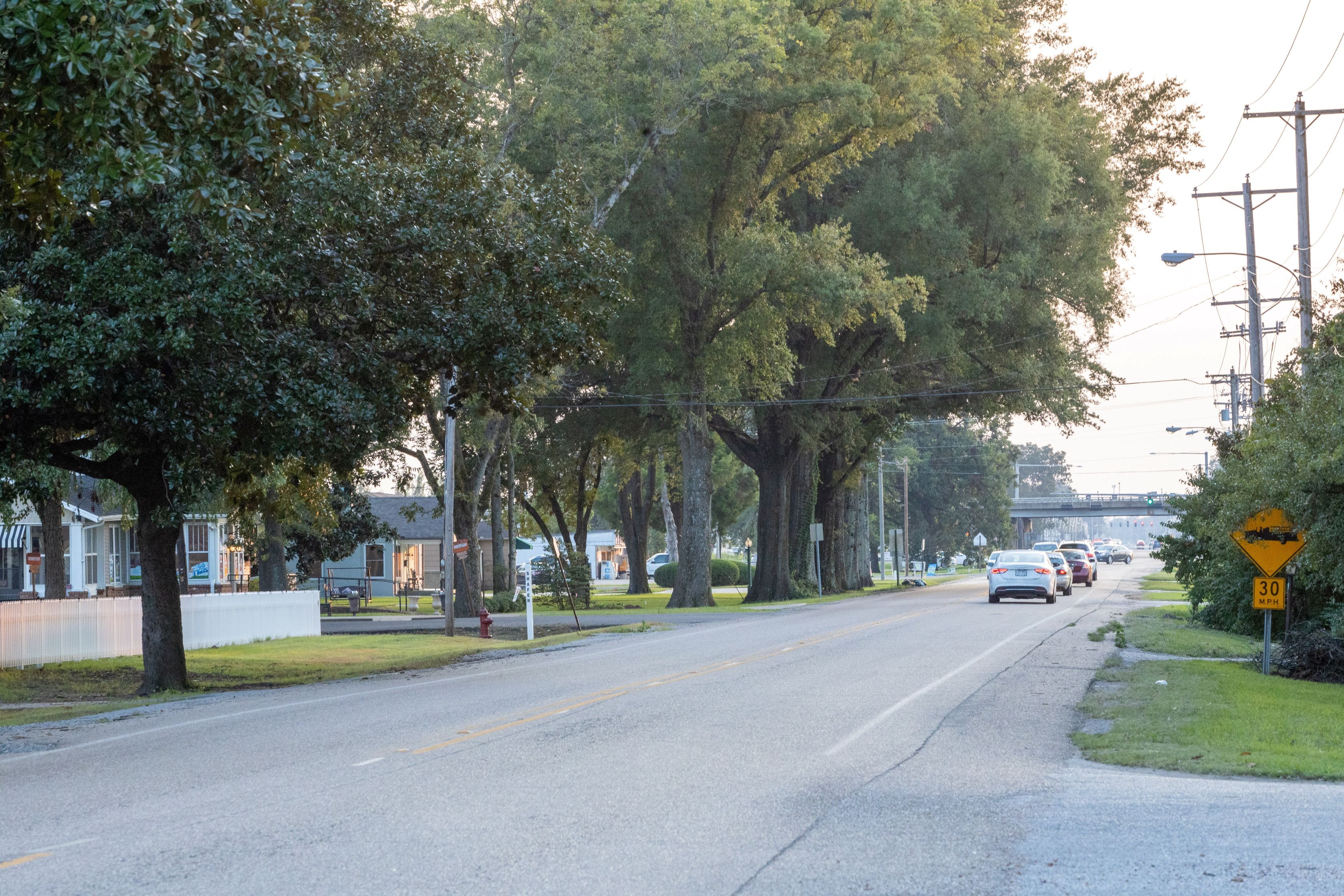 image of a two lane road with houses and cars