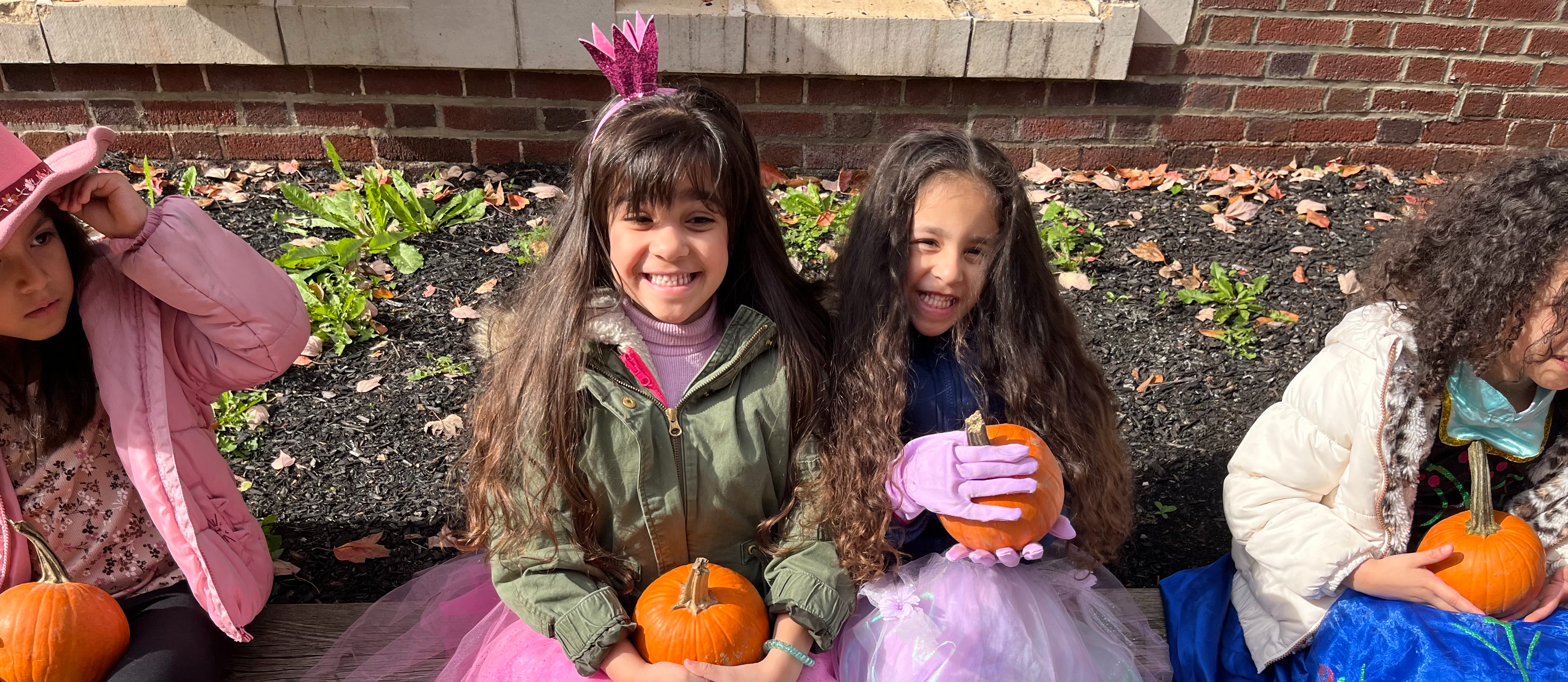 two girls in princess skirts posing with pumpkins for Halloween