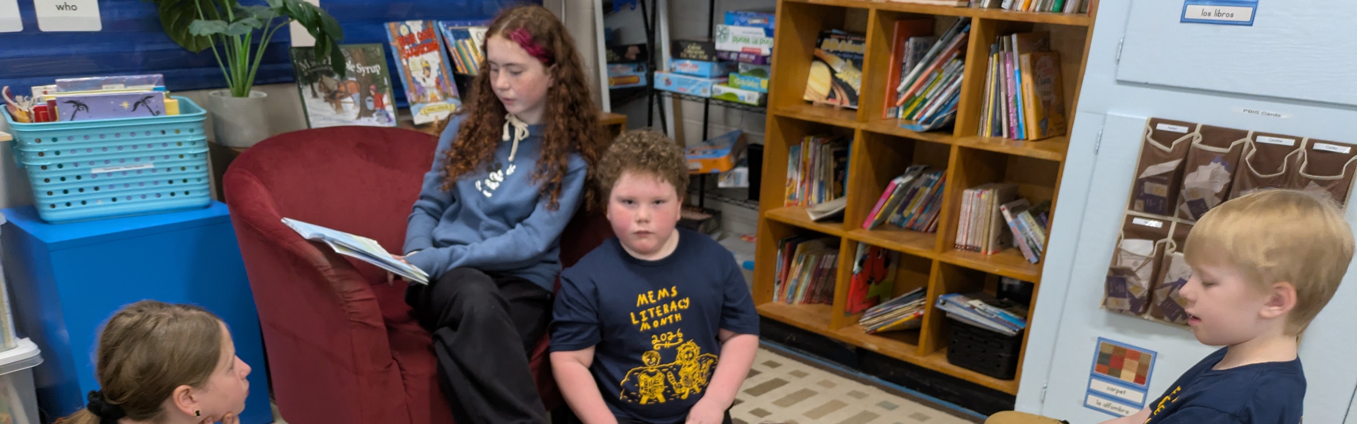 girl in a chair reading to three children