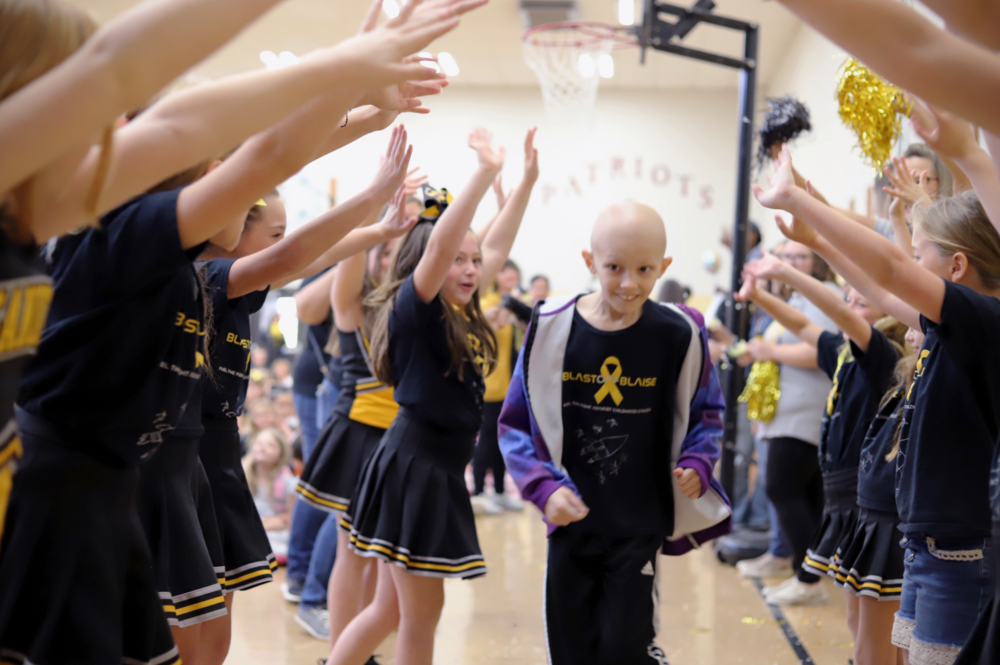 Blaise Schrepel runs through his classmates' outstretched arms as they celebrate his return to school