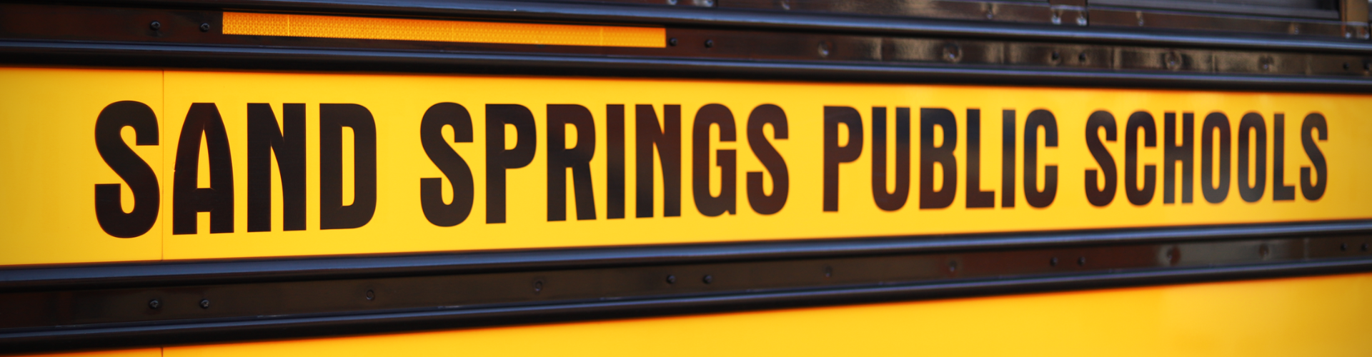 Side of a school bus with text reading: Sand Springs Public Schools