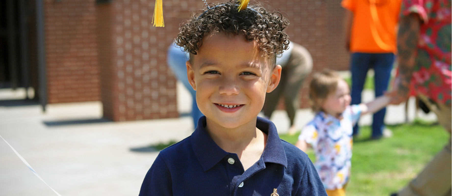 Preschool student wearing headband with small graduation caps made of felt