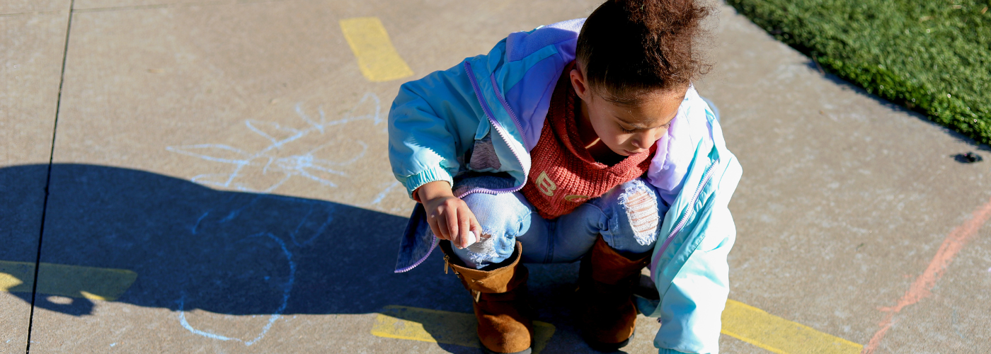 pre-K students using chalk on sidewalk