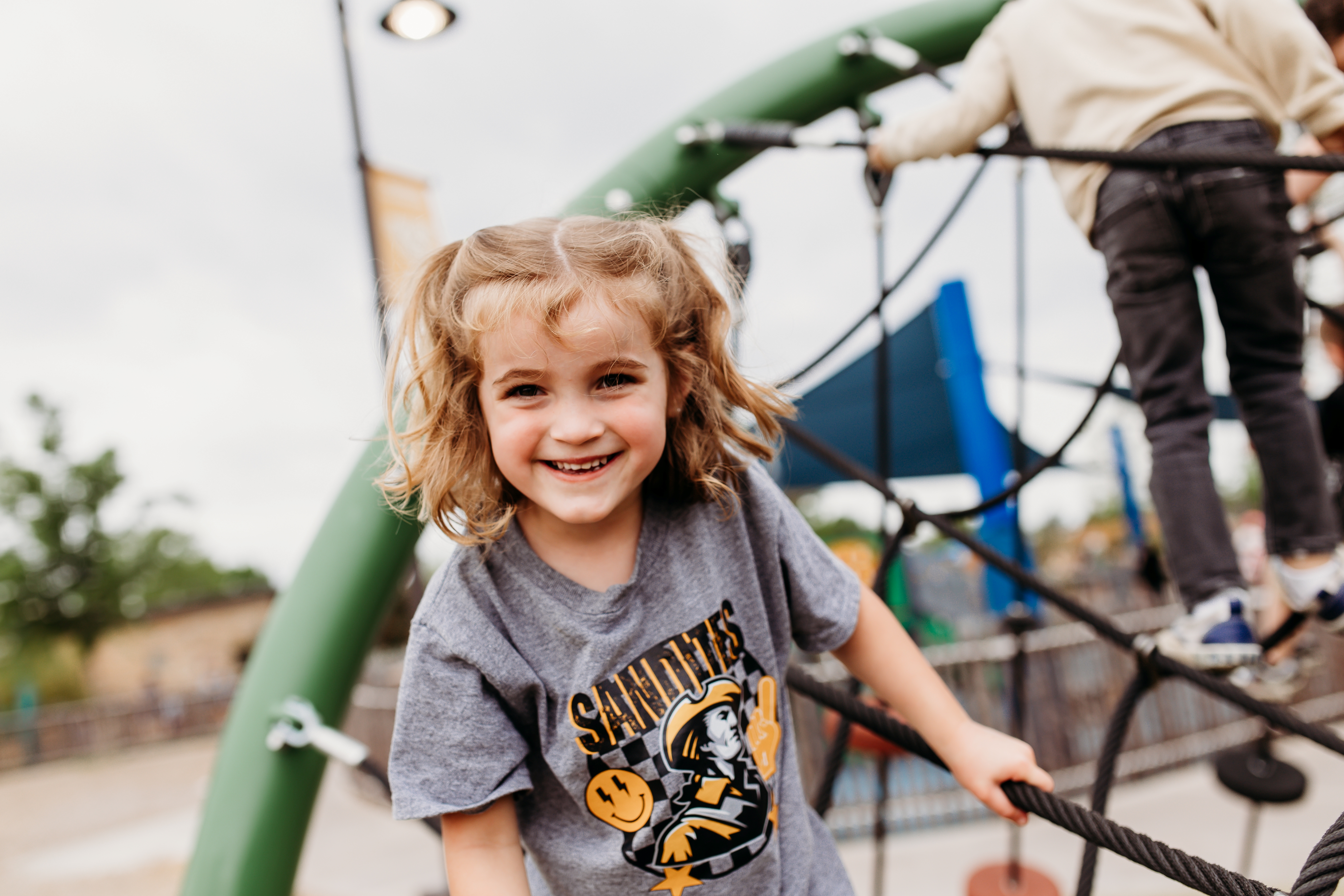 pre-k student in Sandites shirt playing on playground
