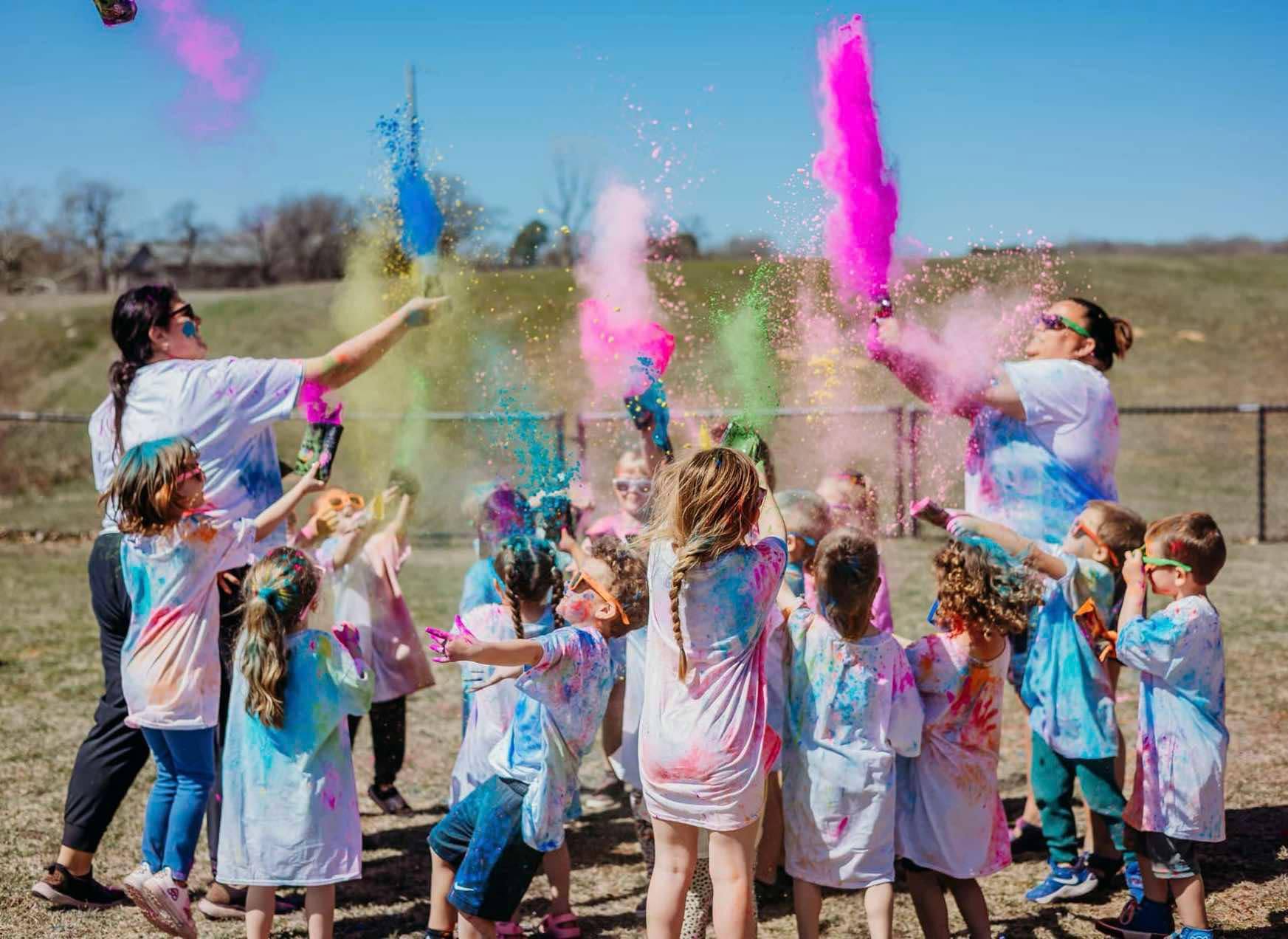 Students and staff throwing colorful powder in the air