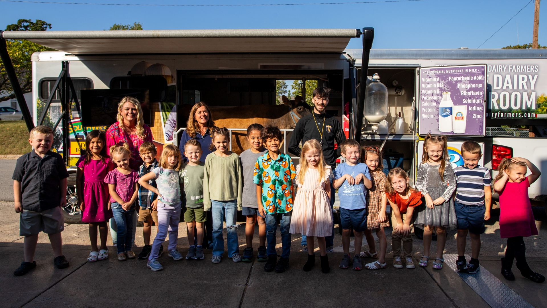 Elementary students and staff gathered in front of mobile dairy trailer with cow