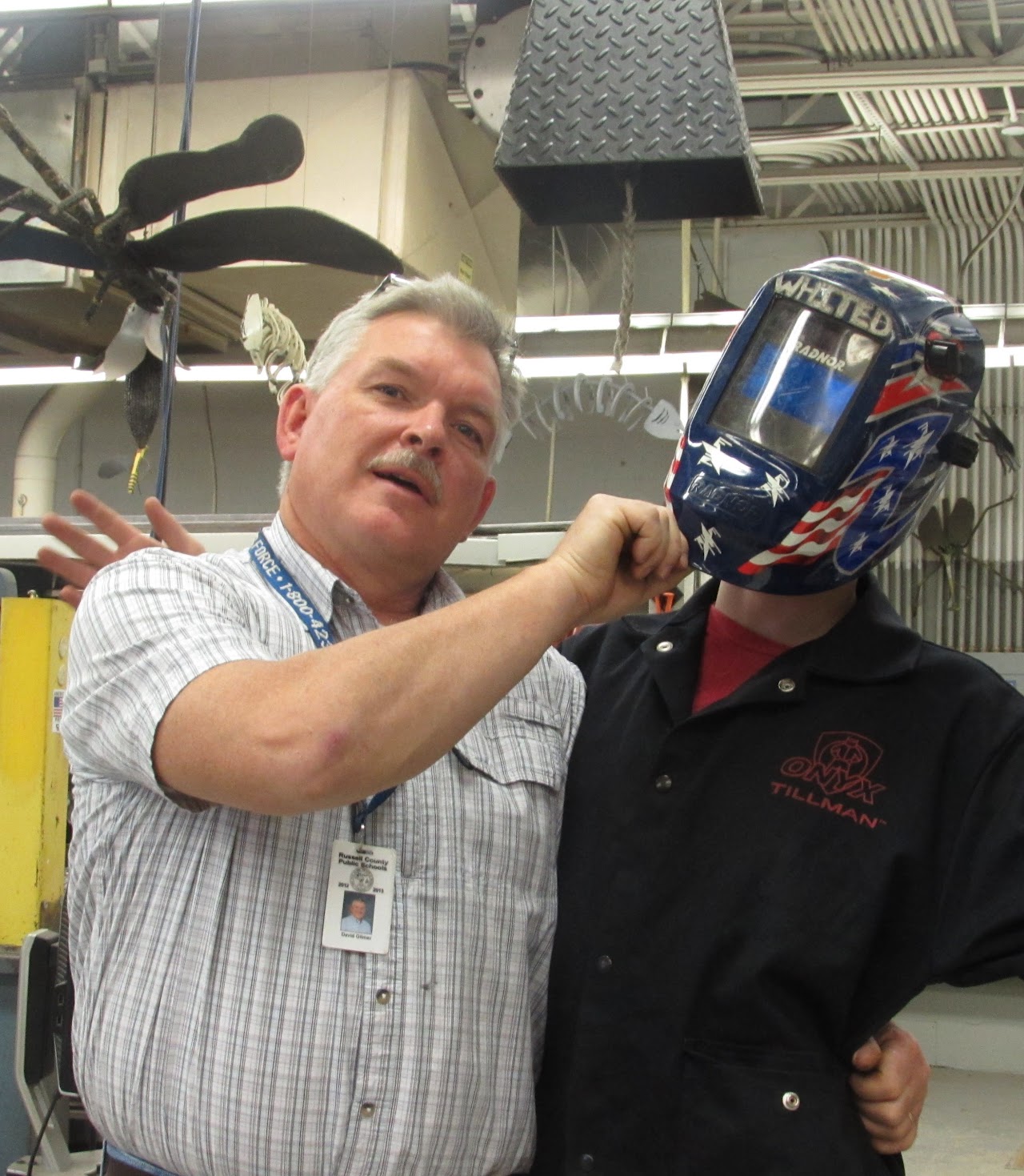 David with student pulling on the students welding protective mask