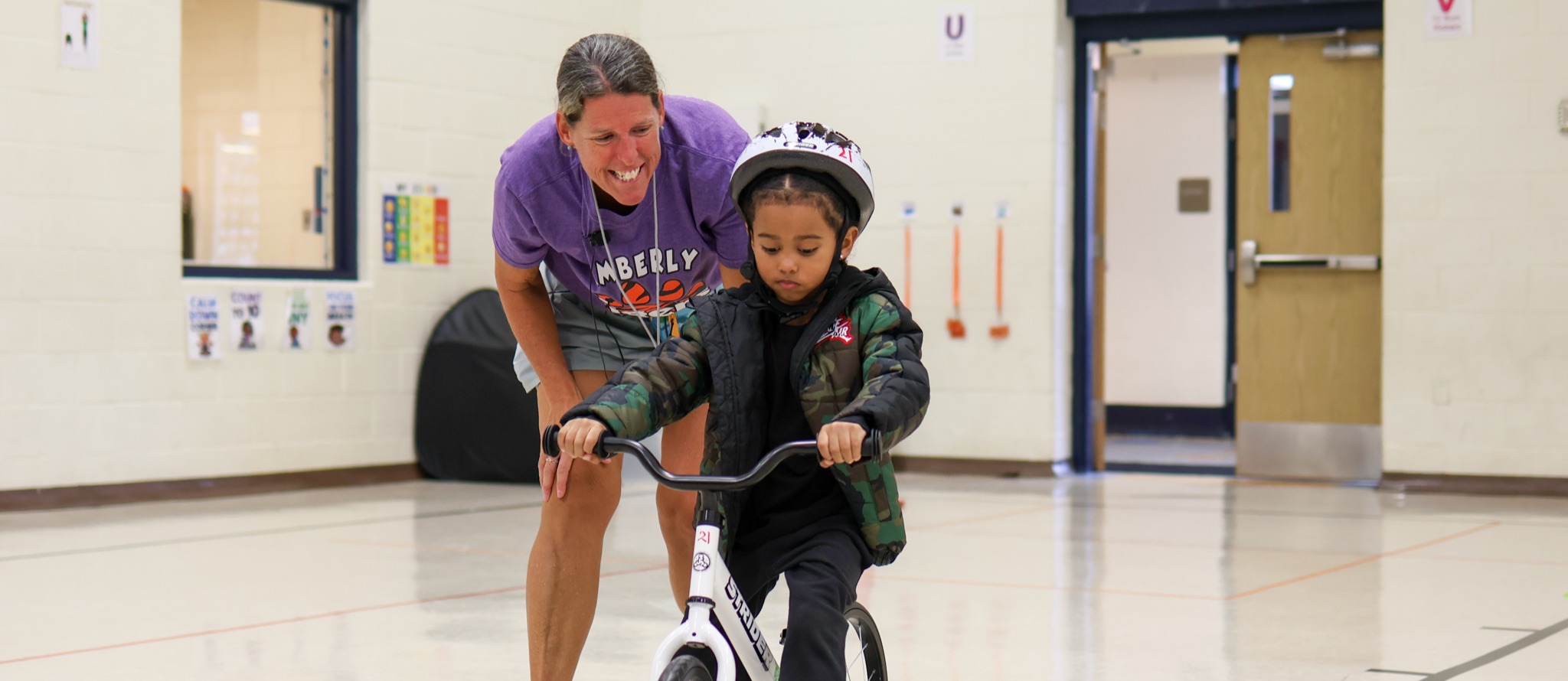 a teacher helping a boy ride a book