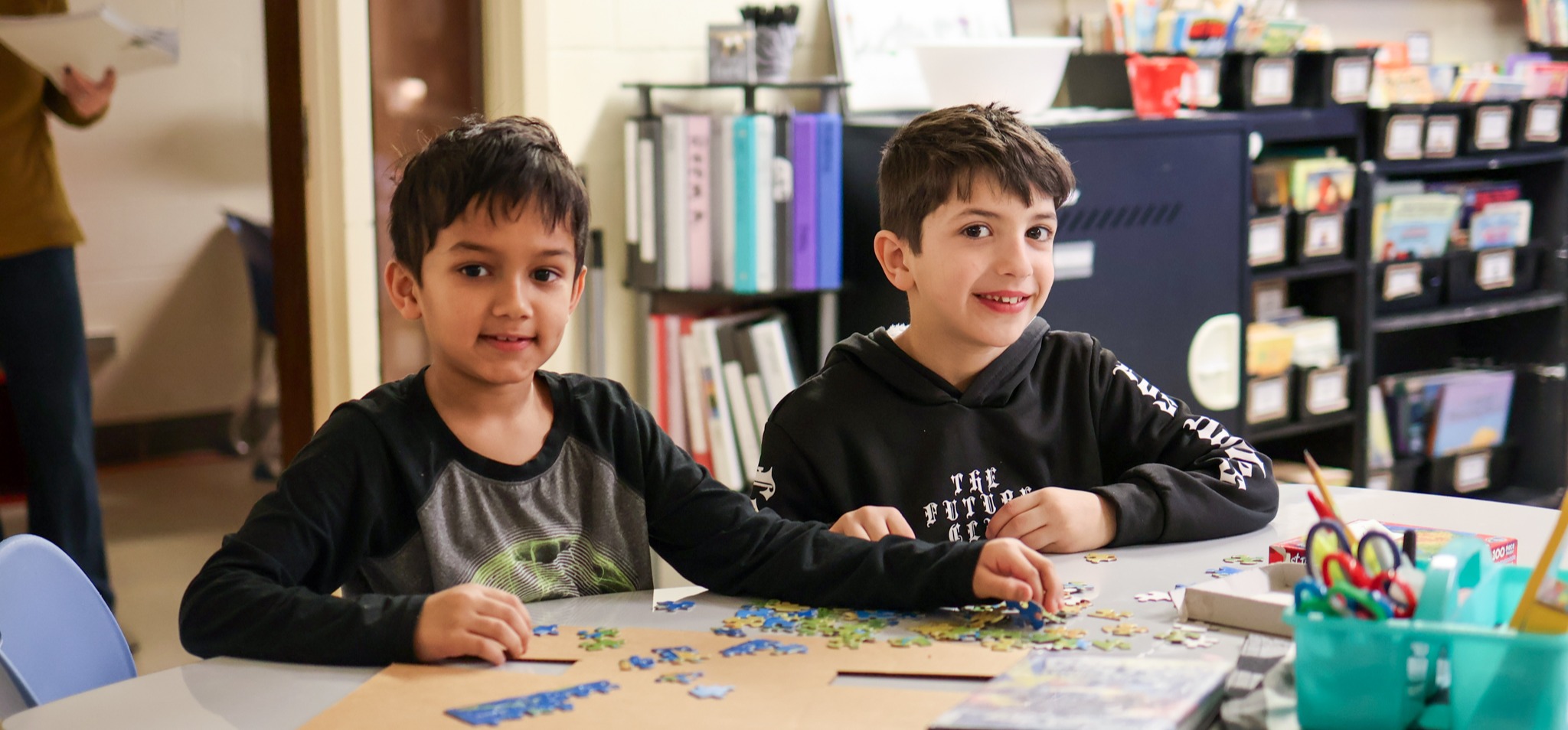 two boys smile for a photo in a classroom