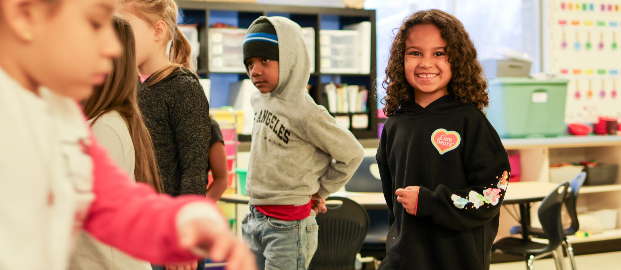 a young girl smiles for the camera in a classroom