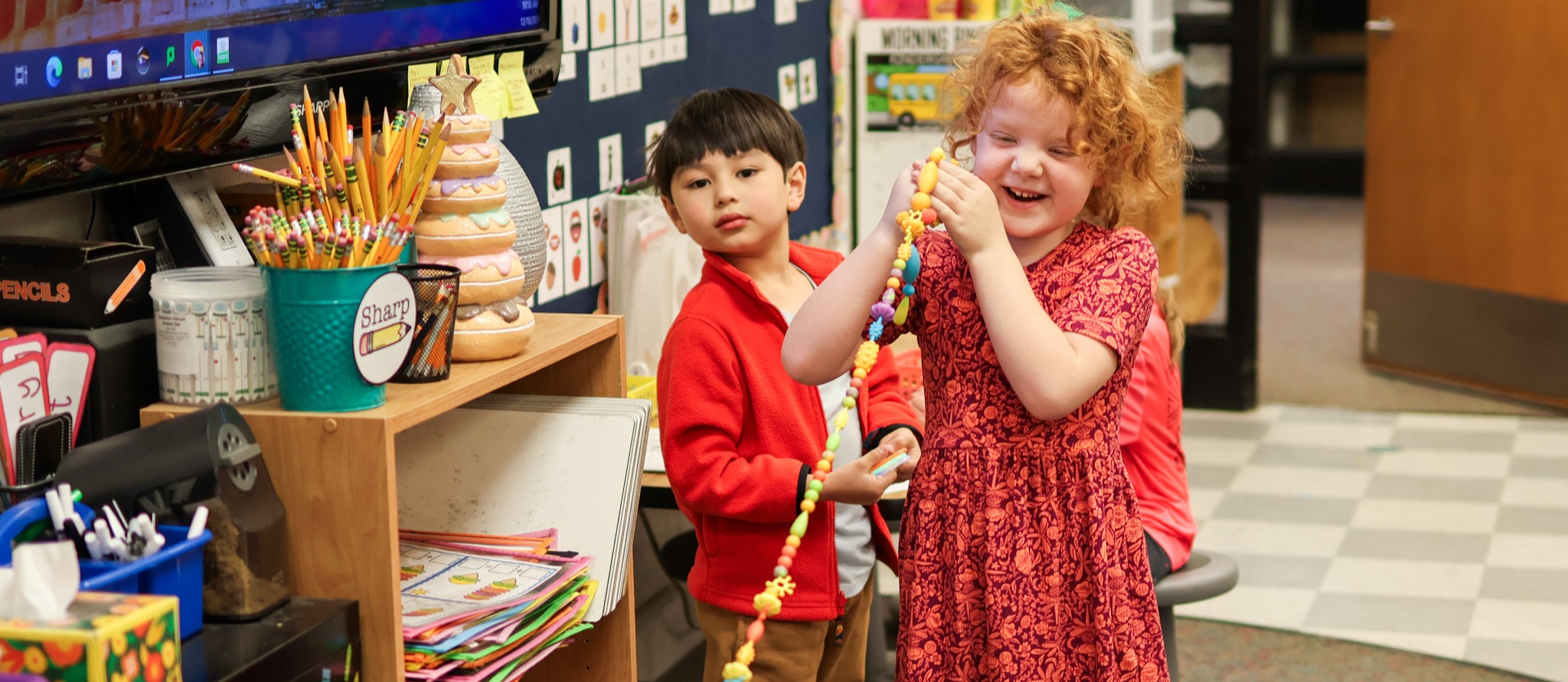 a girl holds up a long string and smiles