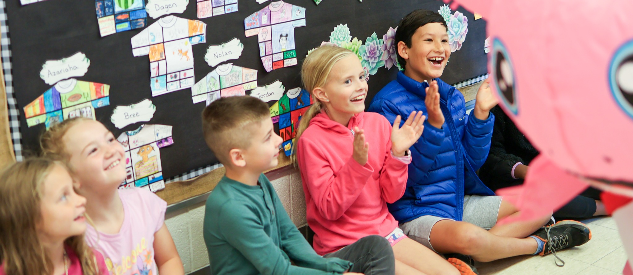 students sitting in a hallway cheering