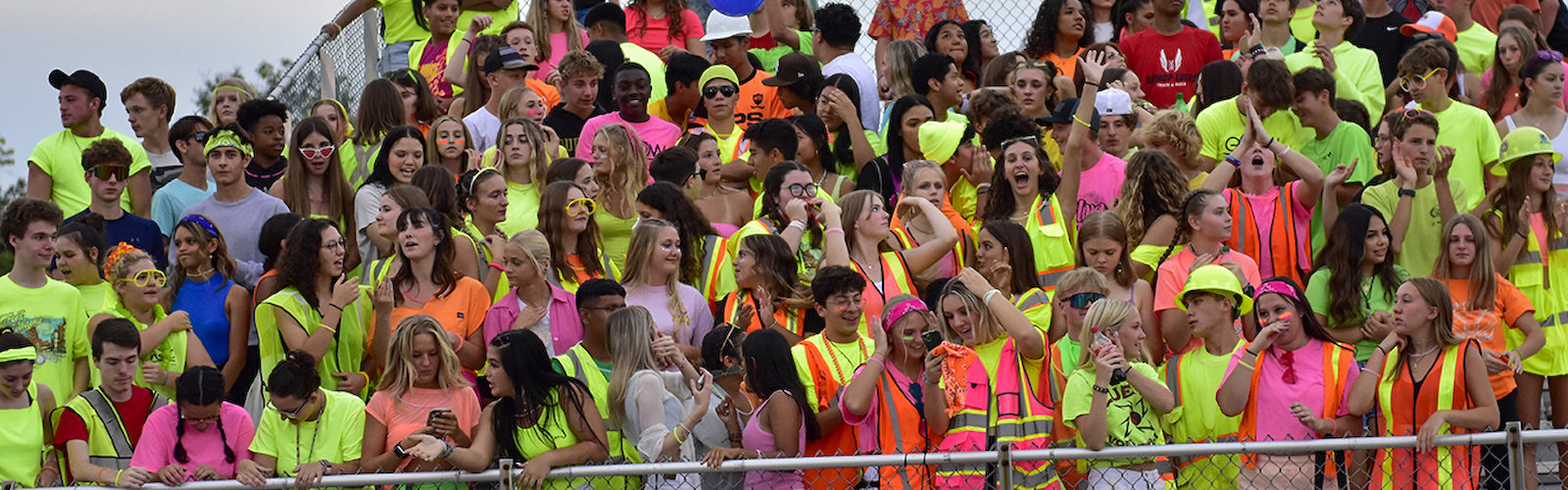 the student section of the football stadium full of students in brightly colored neon safety vests