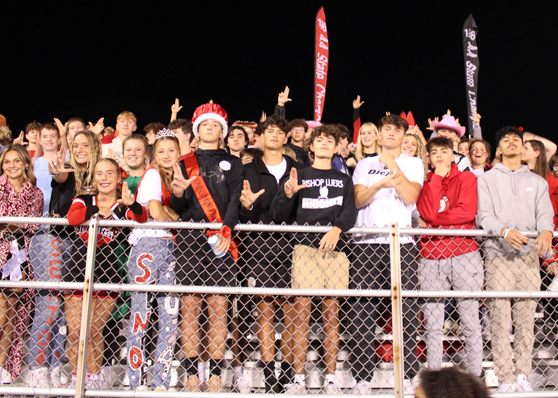 a group of students in Hawaiian shirts cheering and raising their arms