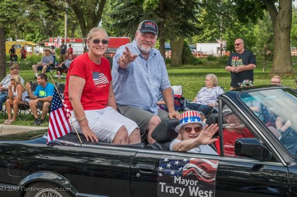 Man and Woman riding on top of vehicle with "Mayor Tracy West" printed