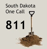 Text: South Dakota One Call 811 besides a shovel in some dirt