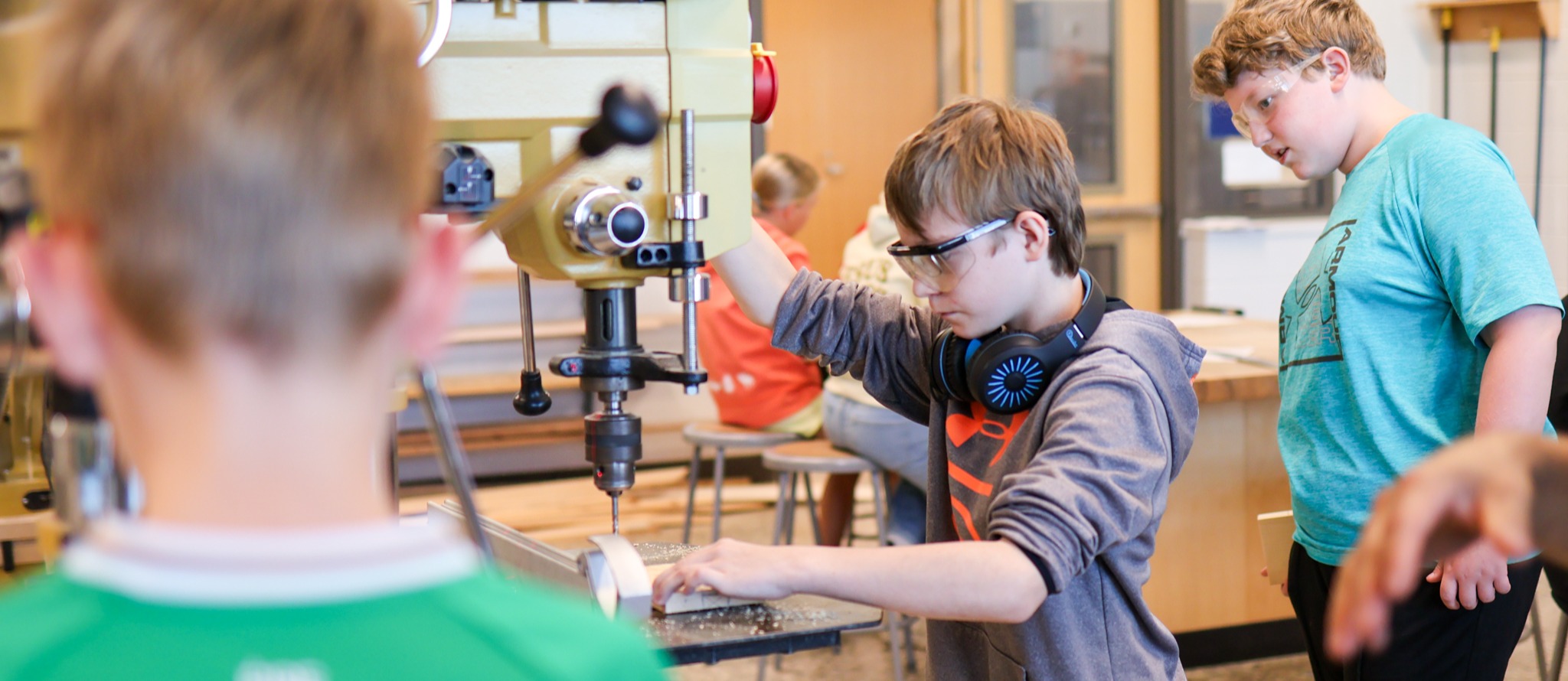 a boy uses a machine in a woodshop