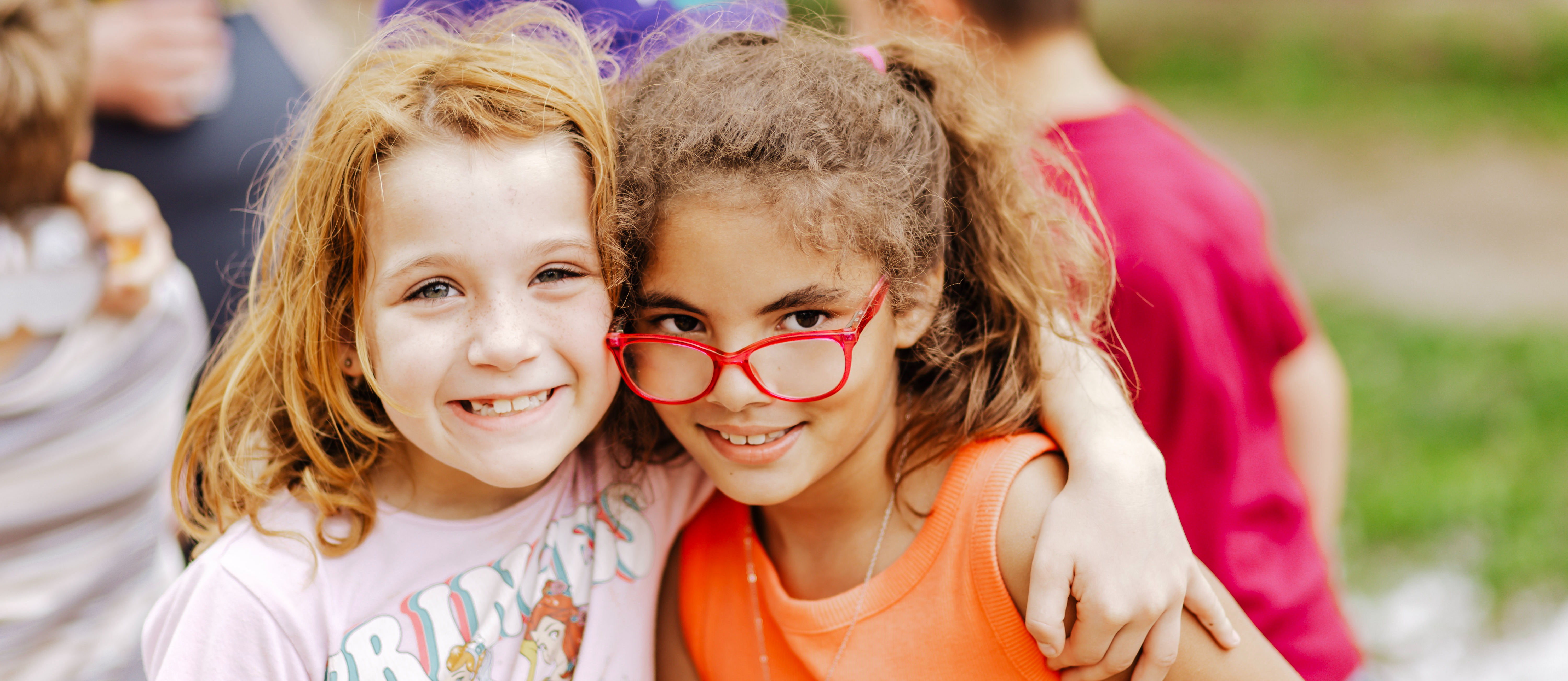 Two elementary students smiling outdoors.