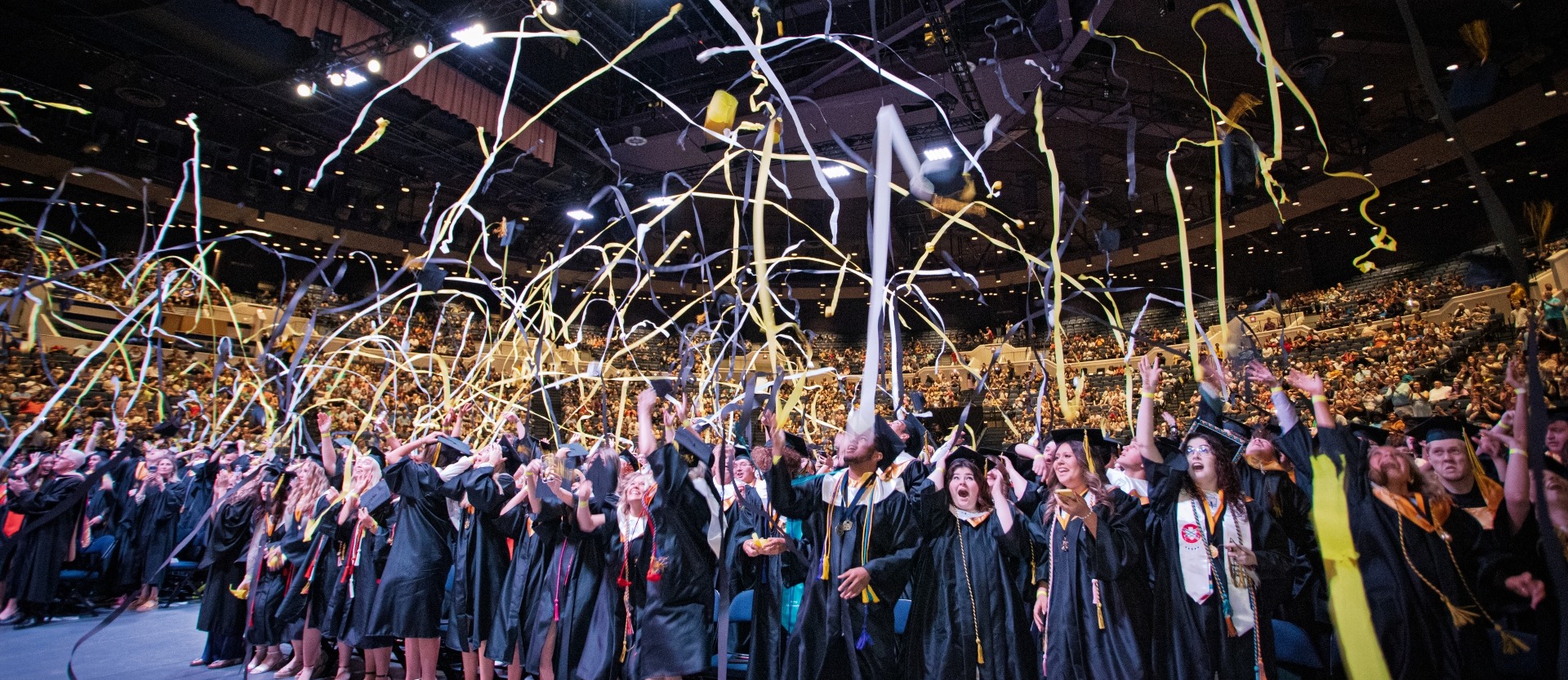students at graduation commencement throwing streamers in the air