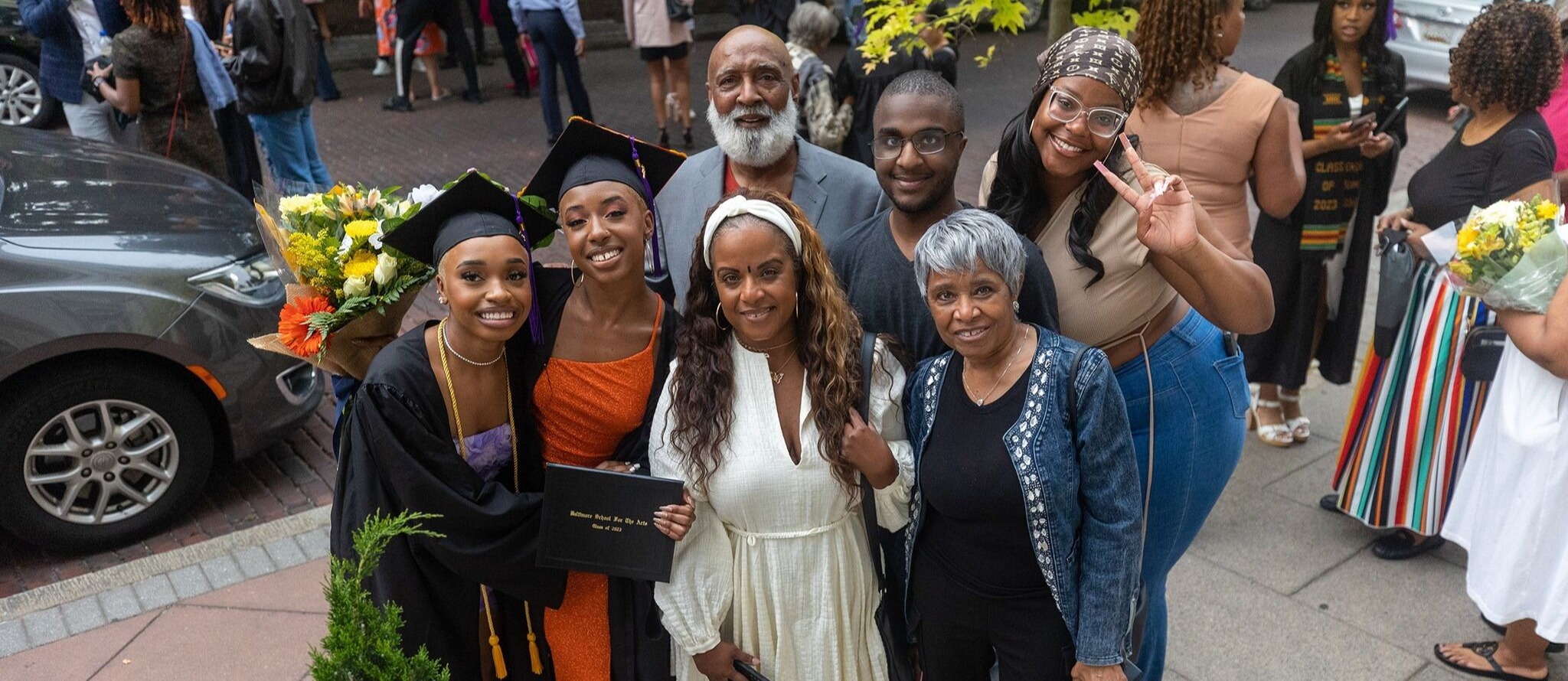 Family stand proudly next to two Baltimore School for the Arts graduates at their 2023 ceremony