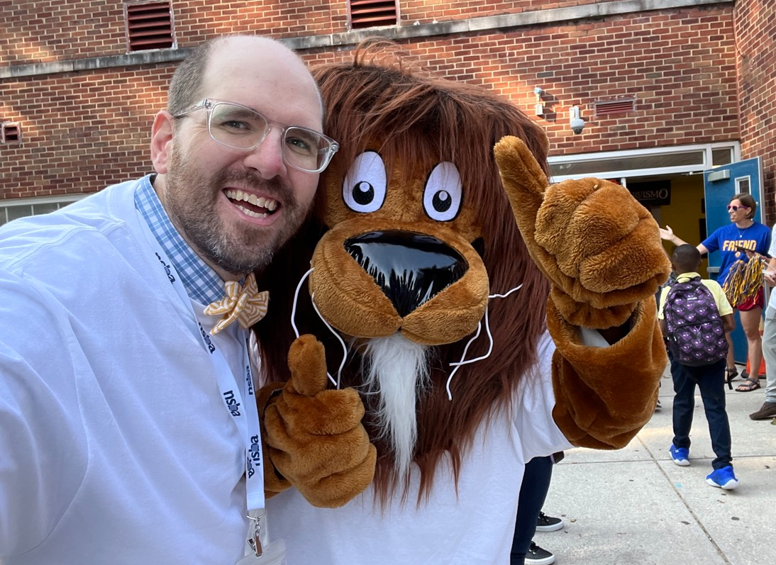 Board member poses with a school mascot. 