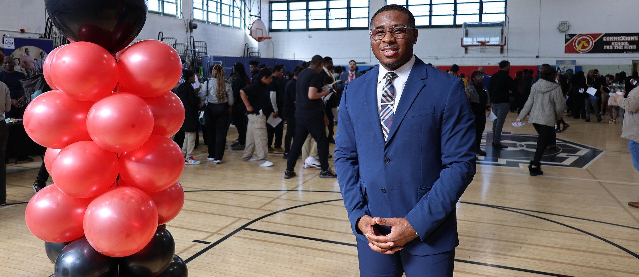 Darius Timmons, the Director of College and Career Placement at ConneXions Academy stands for a photo in the middle of the school gym during career fair. 