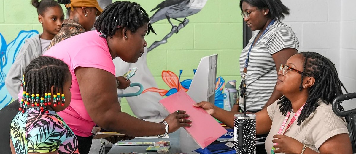 Parent reaches for a piece of paper across the table at the Lillie May Carroll Jackson Charter School Back to School Bash
