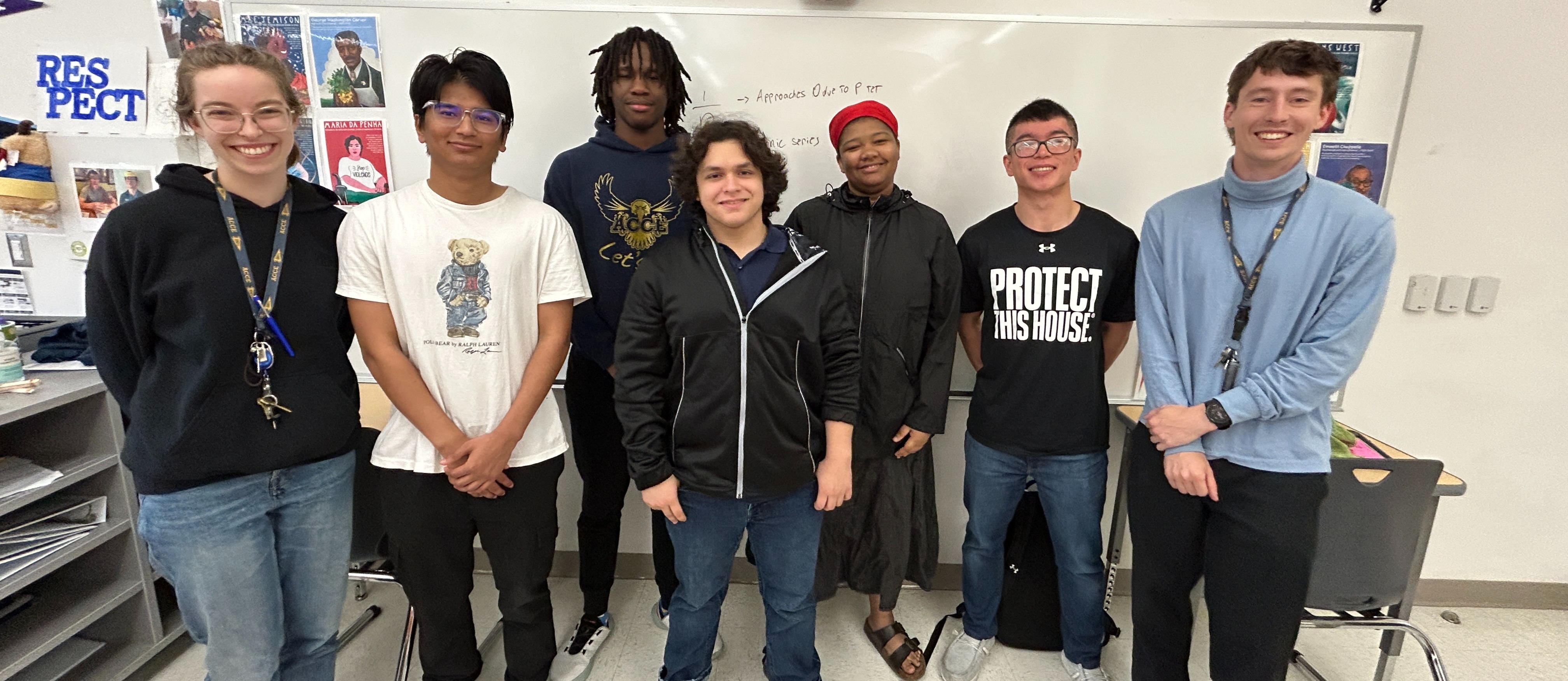 Oscar, Jordan and classmates pose for a photo up against a classroom whiteboard.