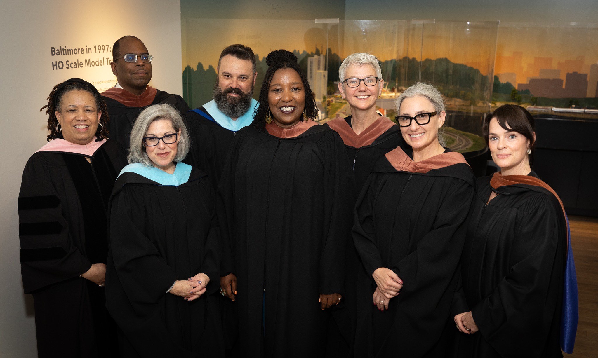 Baltimore School for the Arts staff line up for picture at graduation dressed in their regalia. 