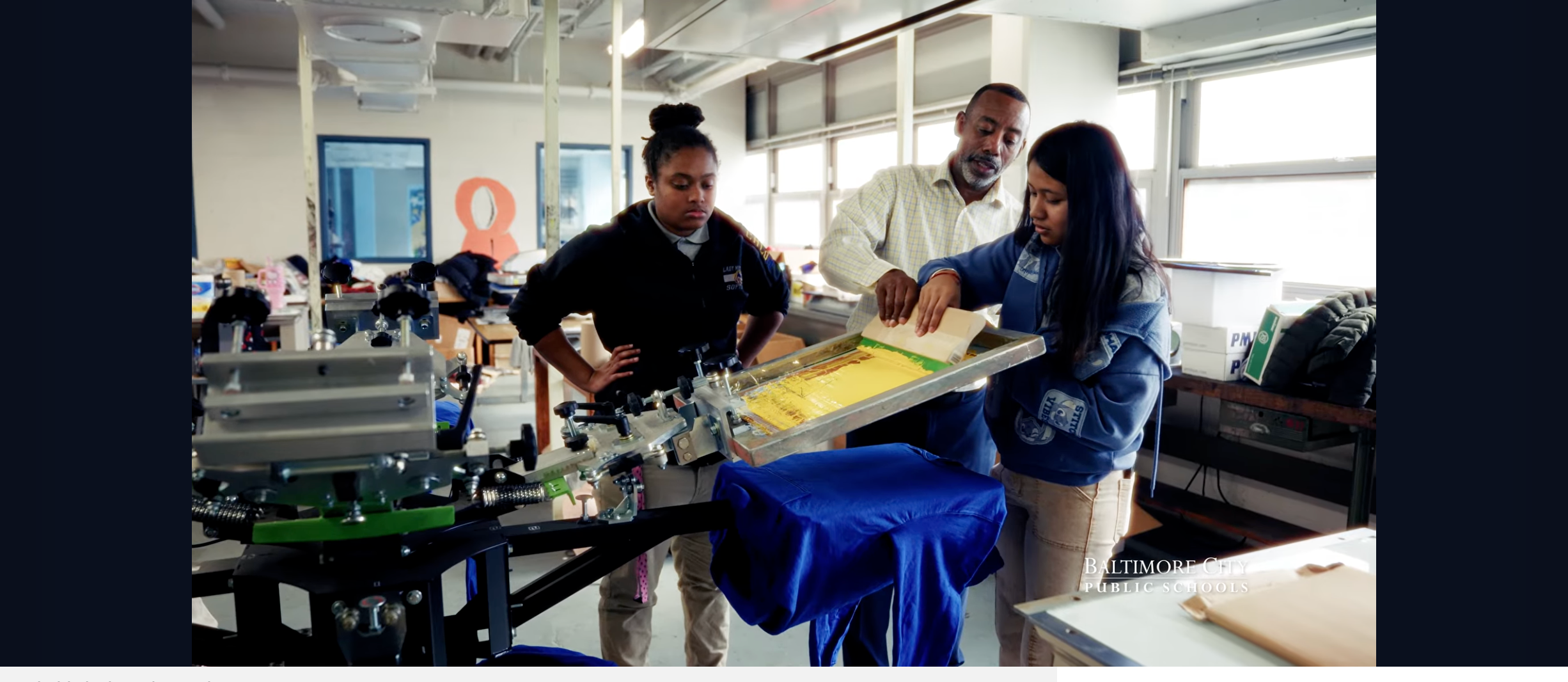 Print teacher at Mervo assists a student print a t-shirt during class.