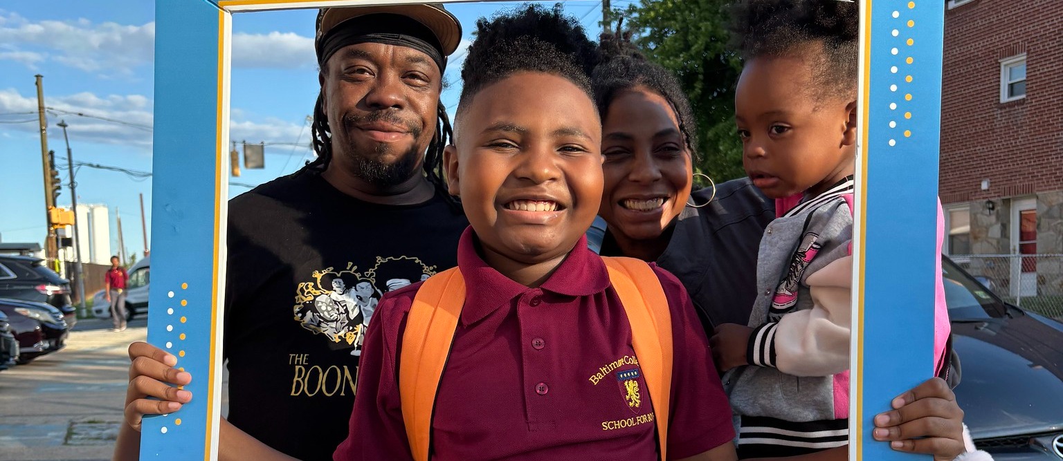 Family poses for a picture with blue City School frame