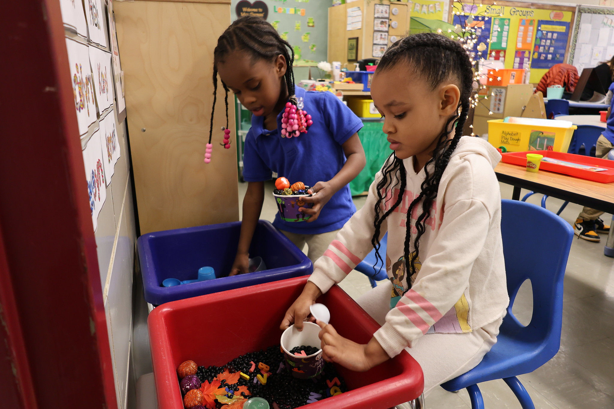 Two pre-K students sorting through a sensory bin