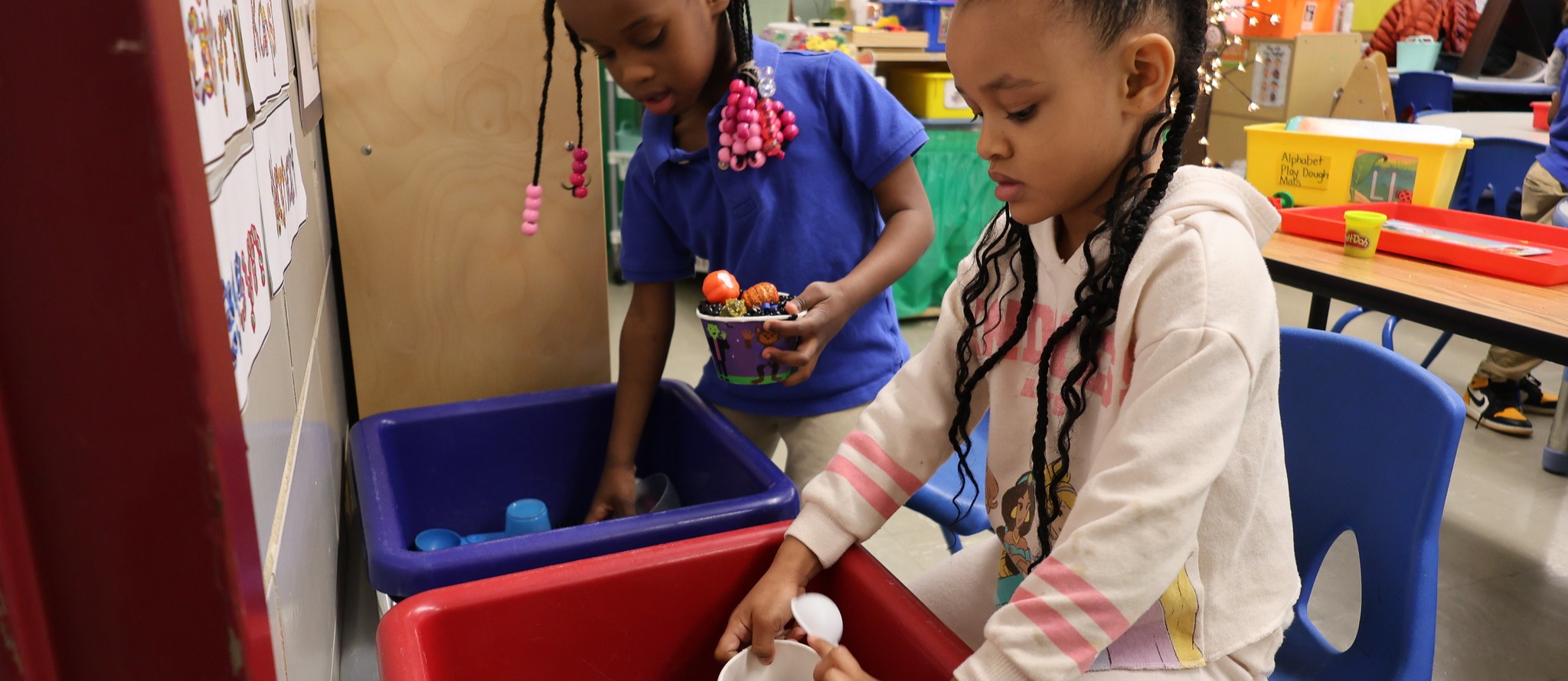 Two pre-K students sorting through a sensory bin